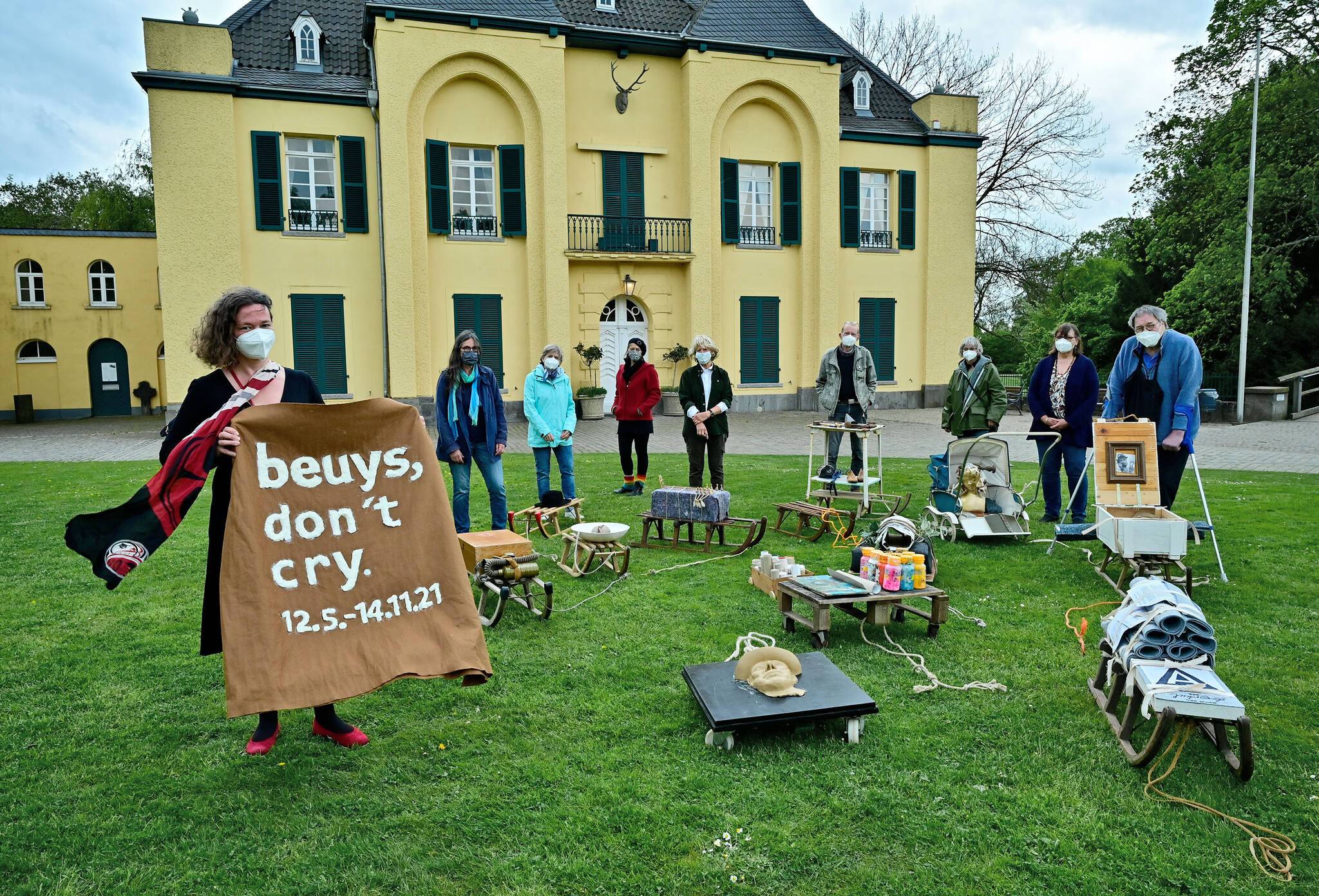Dr. Jennifer Morscheiser, Leiterin Museum Burg Linn, vor der Kunstinstallation zu Beuys 100. Geburtstag. Dahinter Künstler des A-Gangs, die in Anlehnung an Joseph Beuys Schlitten künstlerisch gestaltet haben. Foto: Stadt Krefeld, Presse und Kommunikation, A. Bischof