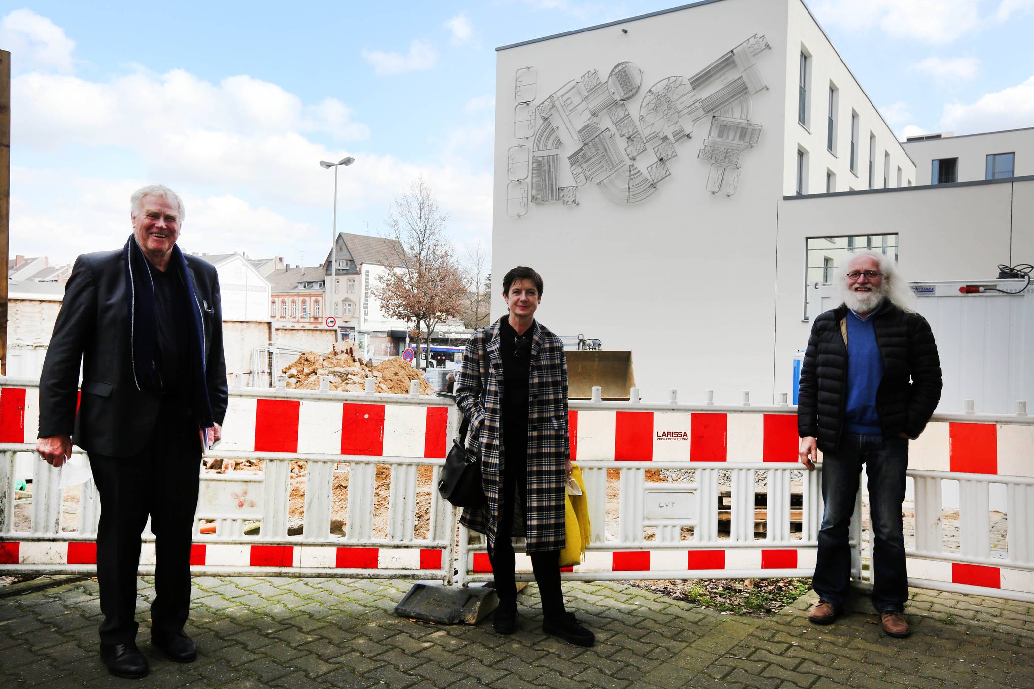 Bernd Gothe (l.), Geschäftsführer Gothe GmbH &amp; Co. KG, Susanne Titz, Direktorin Museum Abteiberg, und Reinhold Schiffers, Aufsichtsratsvorsitzender GWSG mbH, vor der Mönchengladbach-Wand an ihrem neuen Standort. 