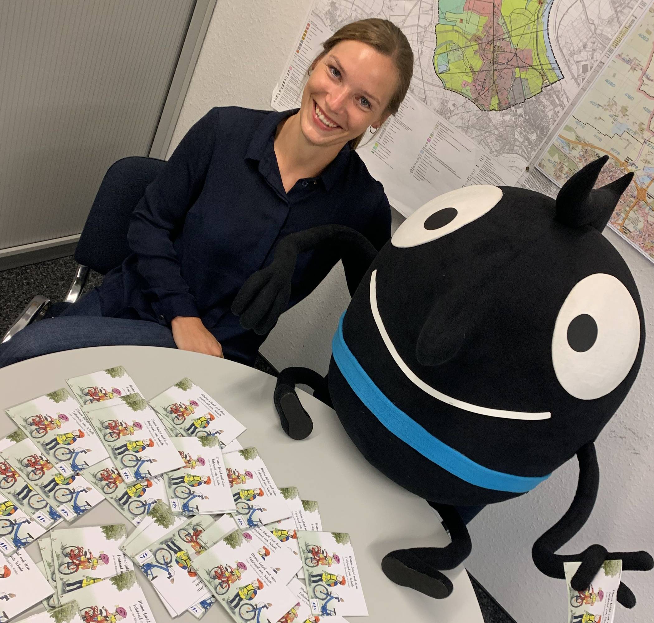 Lena Clermont von der Stabsstelle Umwelt- und Klimaschutz freut sich mit „Edgar“, dem Maskottchen der Europäischen Mobilitätswoche, über das gelungene Mini-Bilderbuch. 