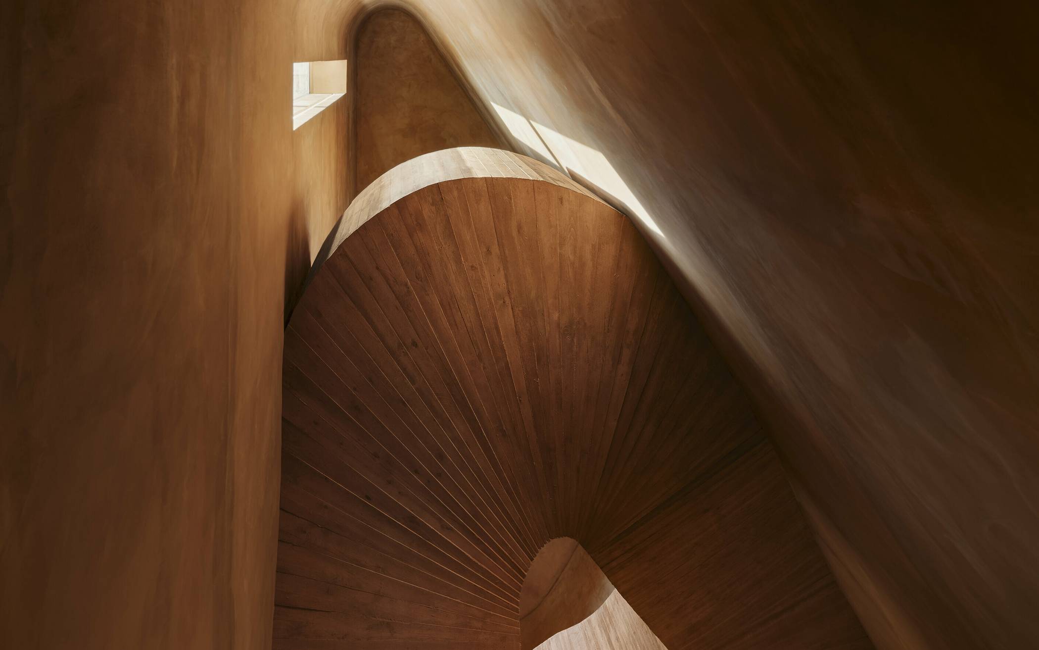  Das neue Treppenhaus aus terrakottafarben bestrichenem Sichtbeton übernimmt Material und Farbgestaltung vom Treppenhaus des Altbaus. 