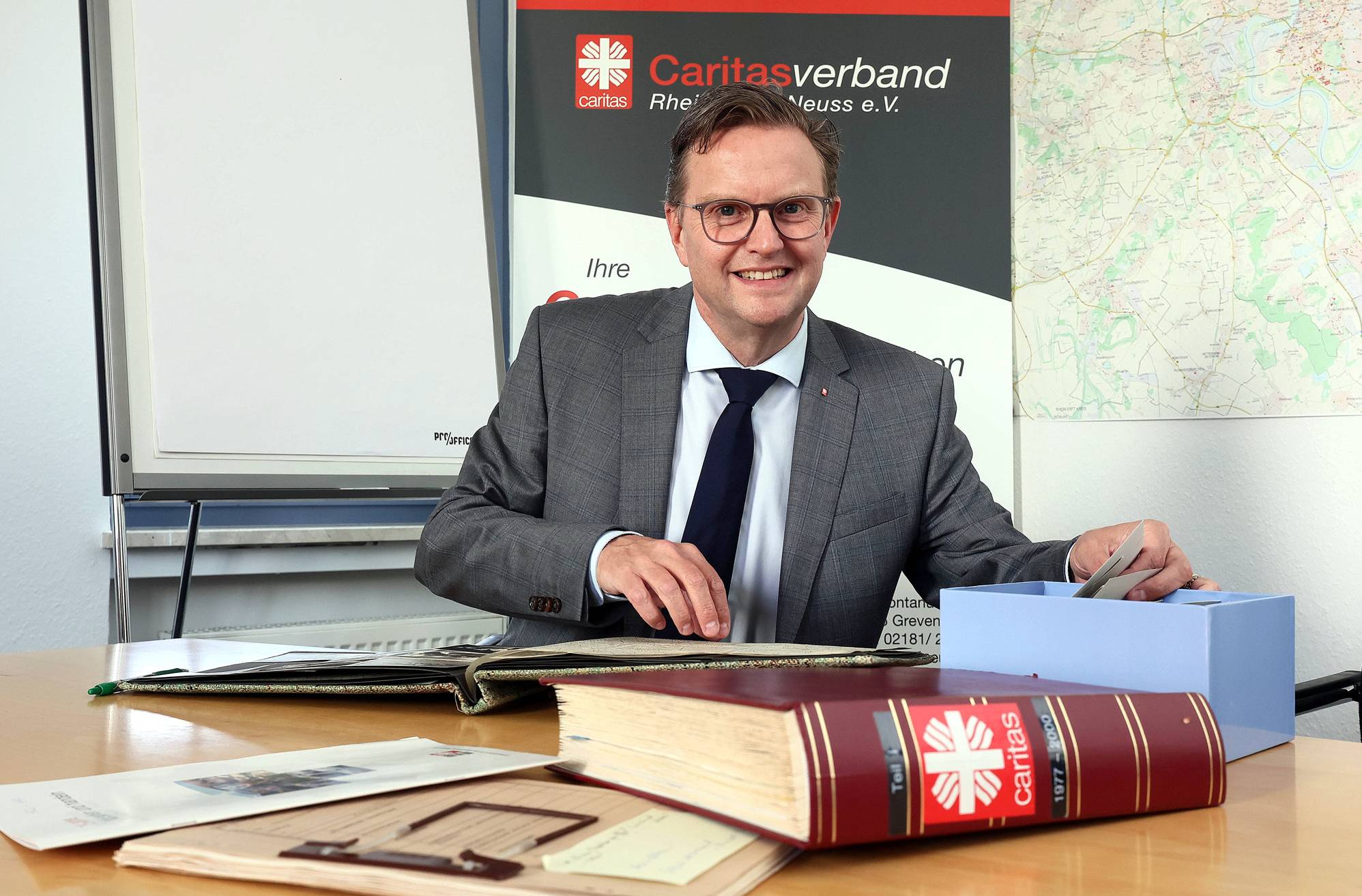 Ruft die Menschen im Rhein-Kreis zum gemeinsamen Erinnern an 100 Jahre Caritas im Rhein-Kreis Neuss auf: Vorstandsvorsitzender Marc Inderfurth mit historischen Fotos und Materialien. 