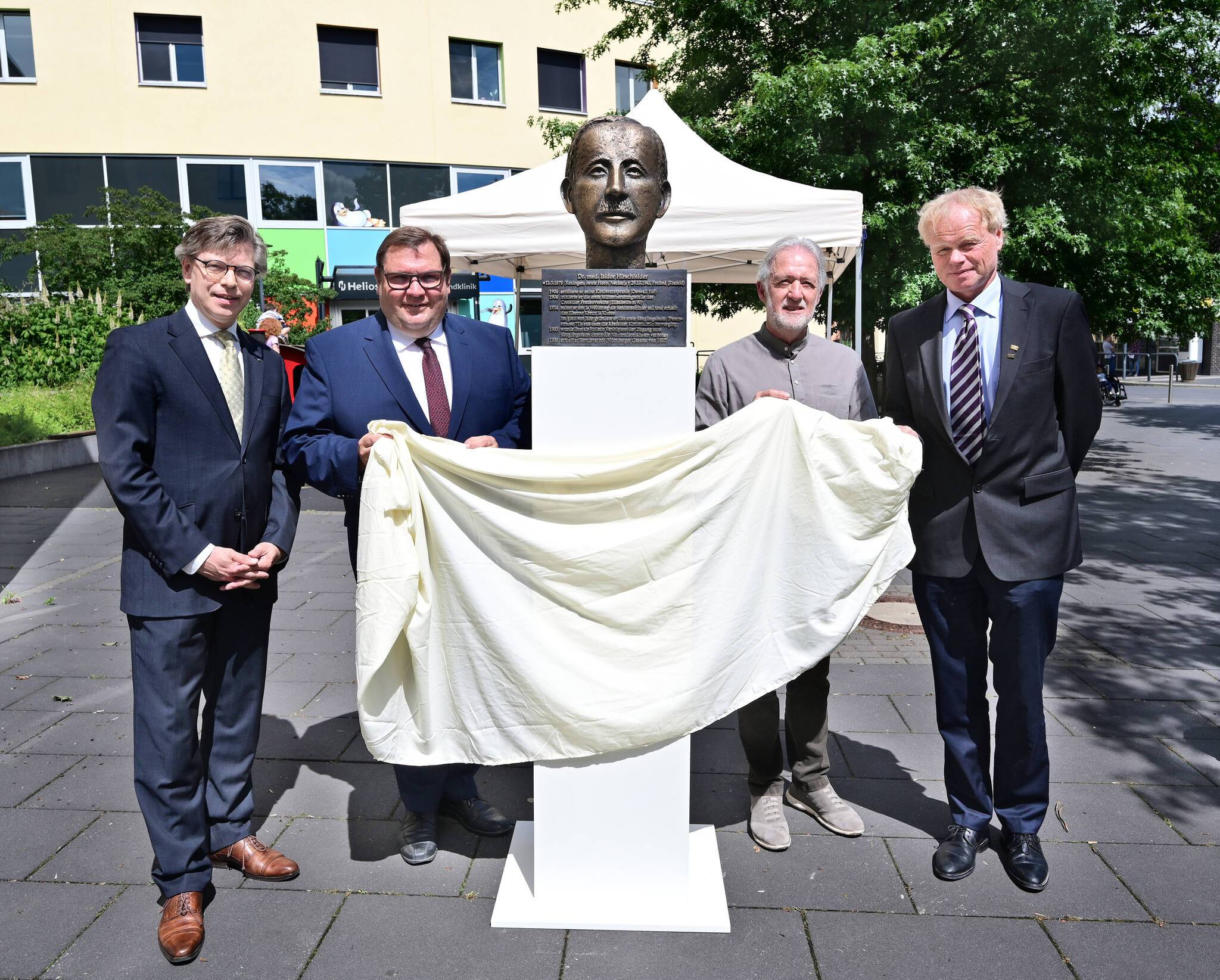 Enthüllen die Büste von Dr. Hirschfelder vor dem Helios-Klinikum: (von links) Dr. Olaf Richter vom Stadtarchiv, Oberbürgermeister Frank Meyer, Bildhauer Michael Franke und Prof. Dr. Tim Niehues, Leiter der Helios Kinderklinik. Foto: Stadt Krefeld, Presse und Kommunikation, A. Bischof