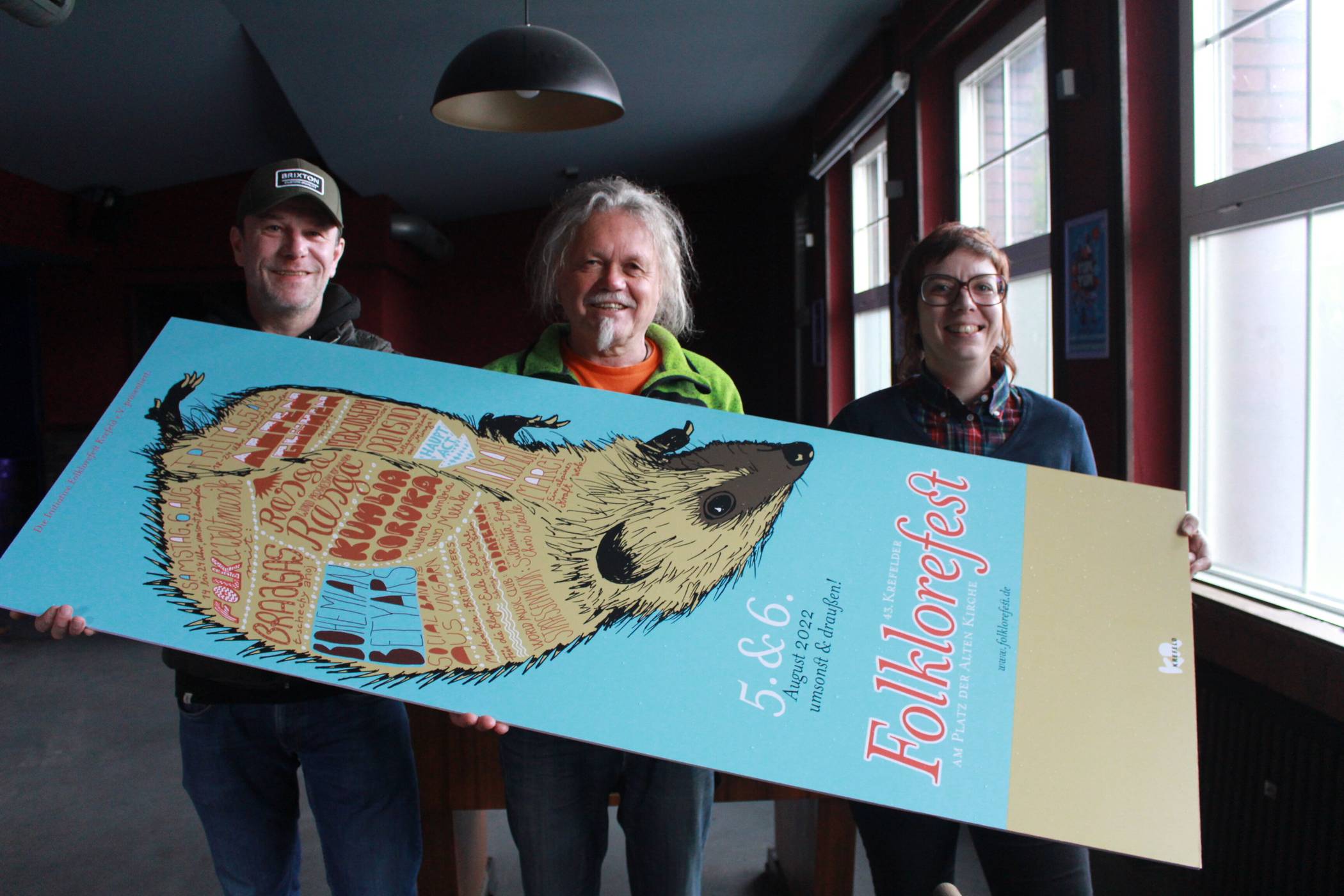  Wappentier Igel: Die Organisatoren (v.r.) Sabrina Grashaus, Jordi Preußer und Michael Spatz präsentieren das Einladungsplakat zum 43. Krefelder Folklorefest am kommenden Freitag und Samstag. Foto: Müller 