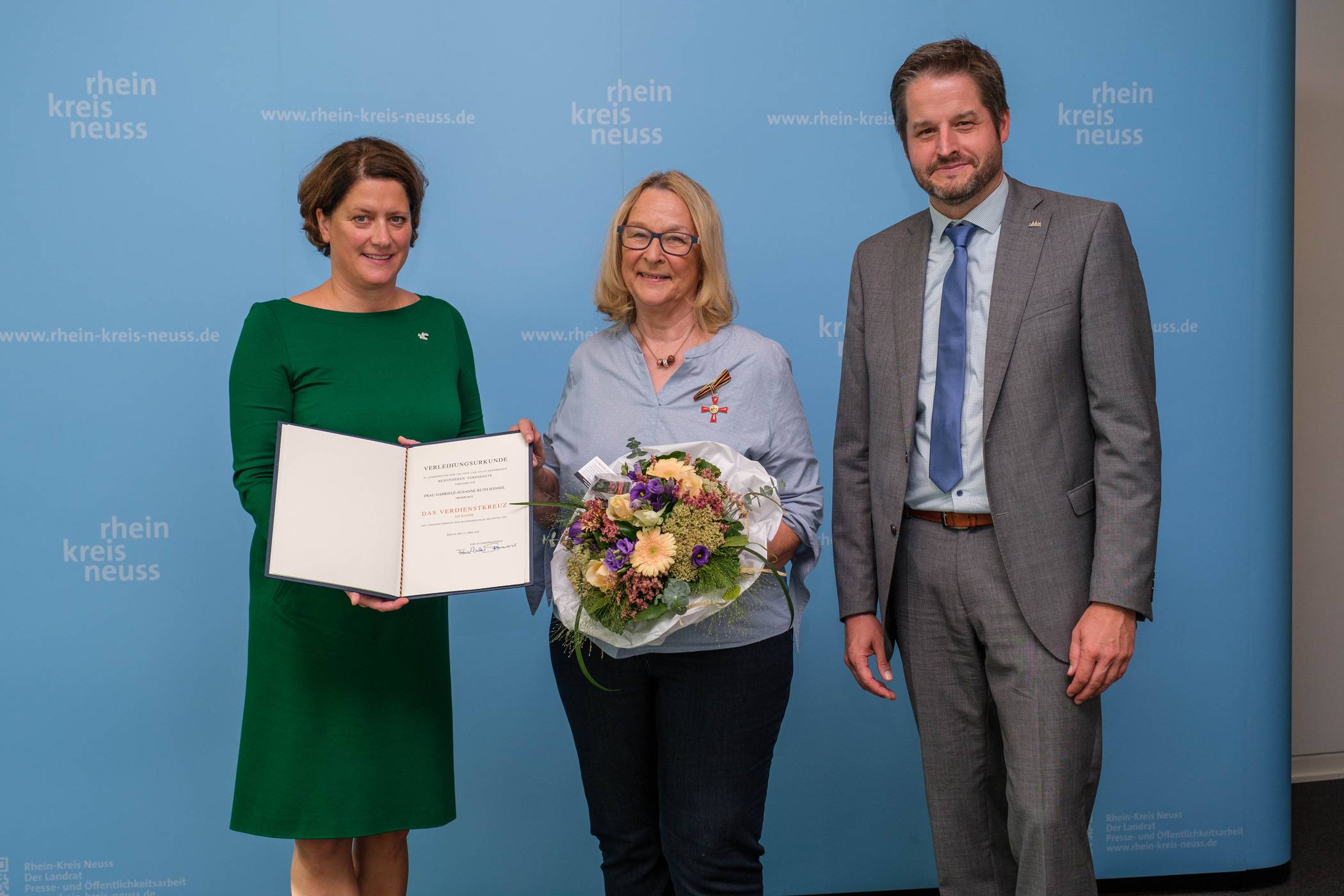  Die 1. stellvertretende Landrätin Katharina Reinhold (l.) überreicht im Beisein von Bürgermeister Christian Bommers das Bundesverdienstkreuz am Bande an Gabriele Hänsel aus Meerbusch. 
  