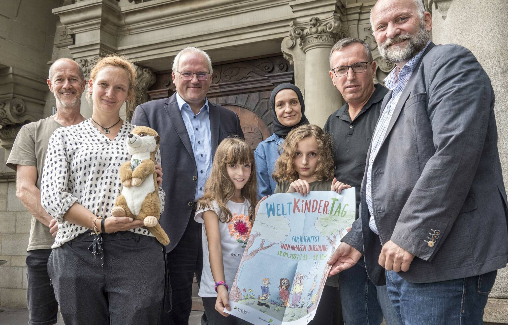  Das Plakatmotiv, das in diesem Jahr für den Weltkindertag in Duisburg wirbt, wurde von der achtjährigen Daria Lusnjani (hier mit ihrer Schwester Daria und den Eltern Hanife und Samet Lusnjani) gestaltet. Oliver Scholten und Katrin Bade (Jugendamt), Paul Bischof (Familiendezernent), und Hinrich Köpcke (Leiter des Jugendamtes) bedankten sich mit einer Familienjahreskarte für den Duisburger Zoo und einem Stofftier bei der Künstlerin.  