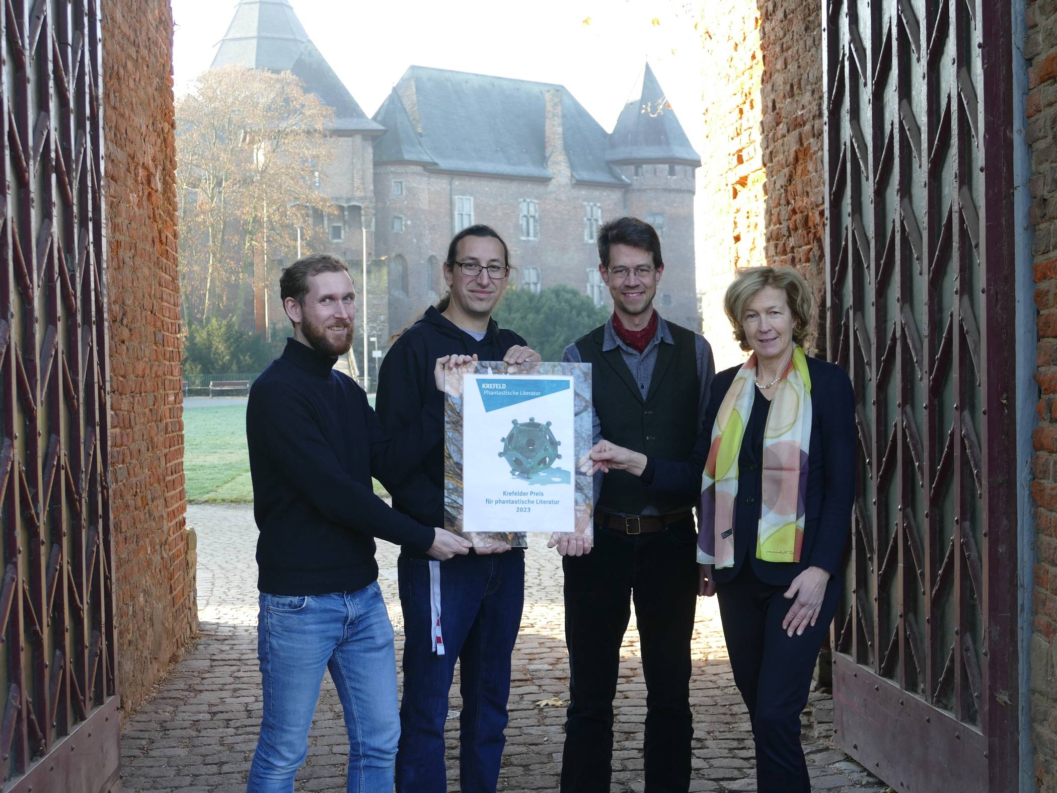 Präsentieren an Burg Linn den Fantastik-Preis: (v. l.)  Museumsleiter Dr. Boris Burandt, der stellvertretende Leiter der Mediothek Simon Hoffmann, Jurymitglied  Matthias Ackermann von der Burg Linn und Krefelds Kulturbeauftragte Dr. Gabriele König. Foto: Stadt Krefeld