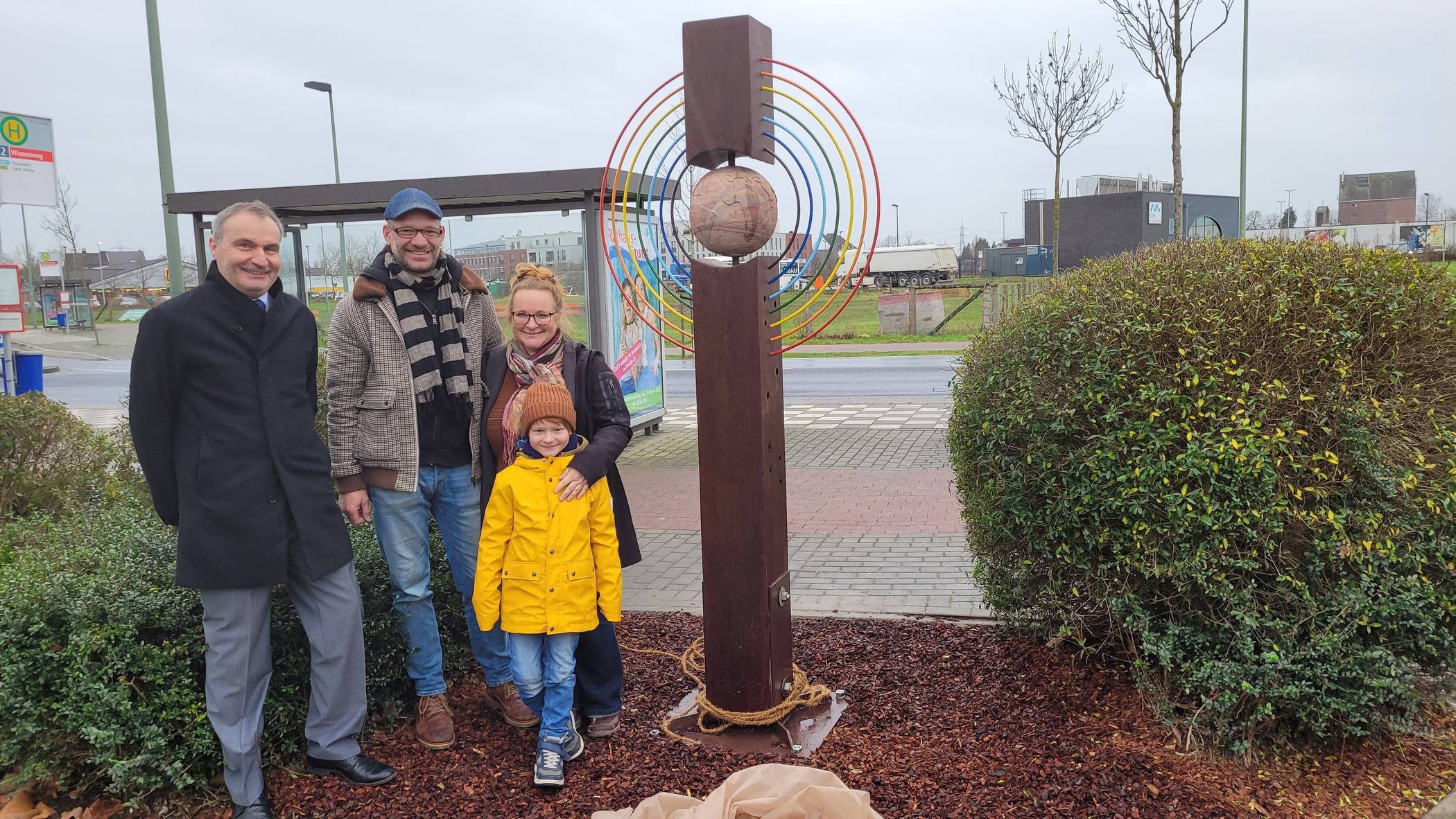 Kultur-Dezernent Peter Annacker, das Künstler-Duo Svenja Neuendorf und Roland Giersch samt ihrem gemeinsamen Sohn Pit vor der Stein-Holz-Stahl-Skulptur „Ein Engel für die Welt“ am Osterather Wienenweg.