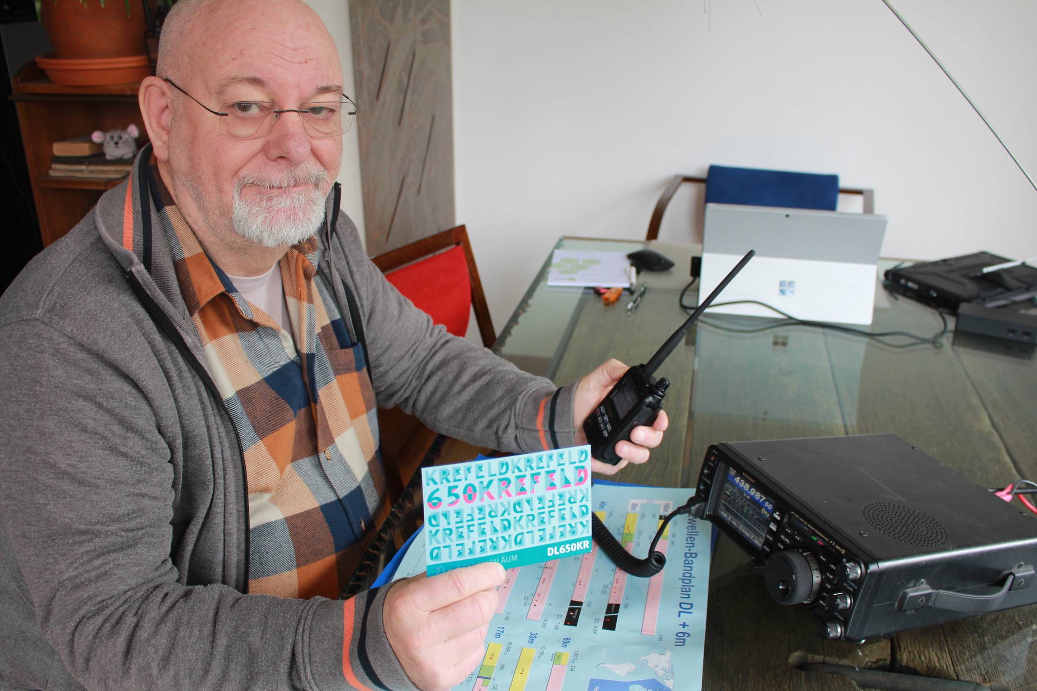 Amateurfunker seit über 40 Jahren: Bernd Furch an seiner Funkanlage, in der Hand die Bestätigungspostkarte mit dem Krefelder Jubiläumslogo. Foto: Müller