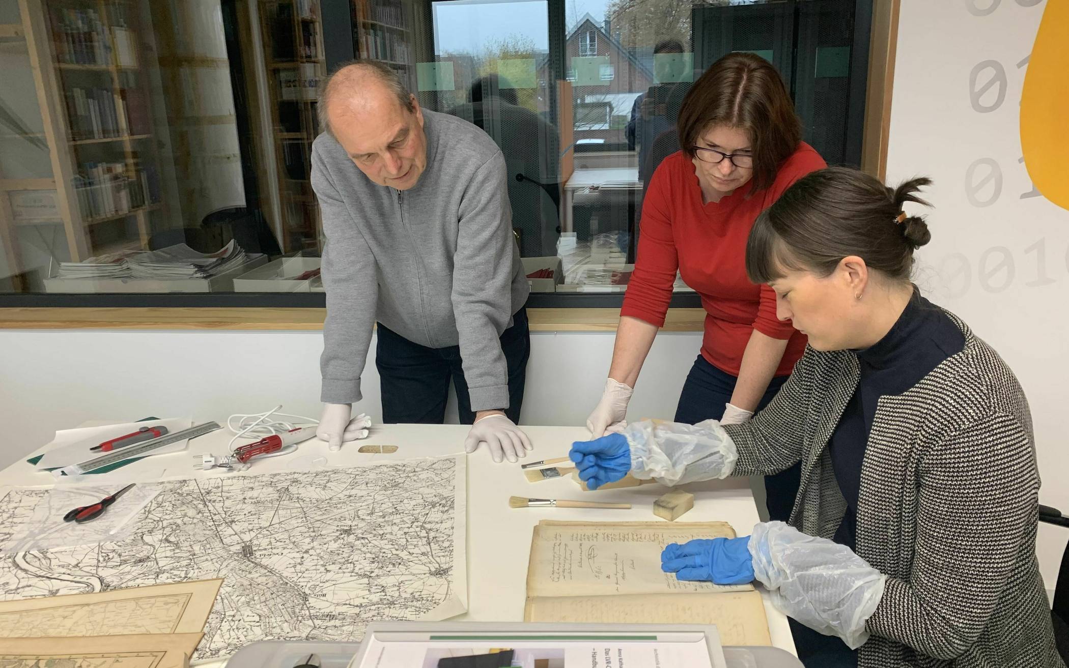Anna Katharina Fahrenkamp (r.), Papierrestauratorin bei der Archivberatungsstelle des LVR, zeigt Stadtarchivar Michael Regenbrecht und seiner Mitarbeiterin die Handhabung der Hilfsmittel. 