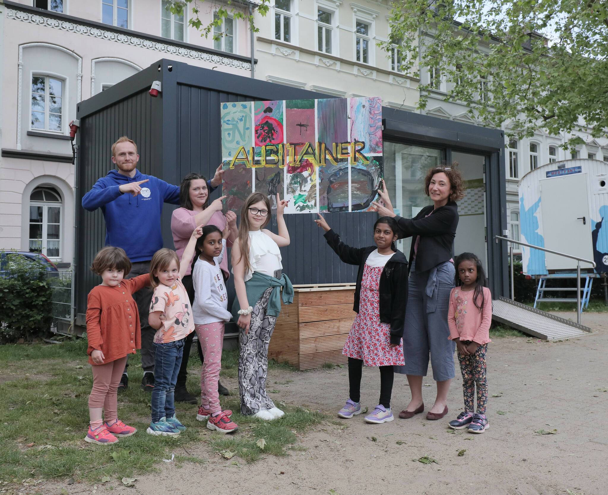  Am Albitainer: (v.l.) Lars Görke, Spielplatzpatin Jennifer Mennein und Aylin Okyar-Köpke von der Jugendhilfe. Mit dabei die Kinder (v.l.) Helena, Johanna, Daranika, Elietta, Abinya und Dakshiga. Foto: Stadt Krefeld, Jochmann 