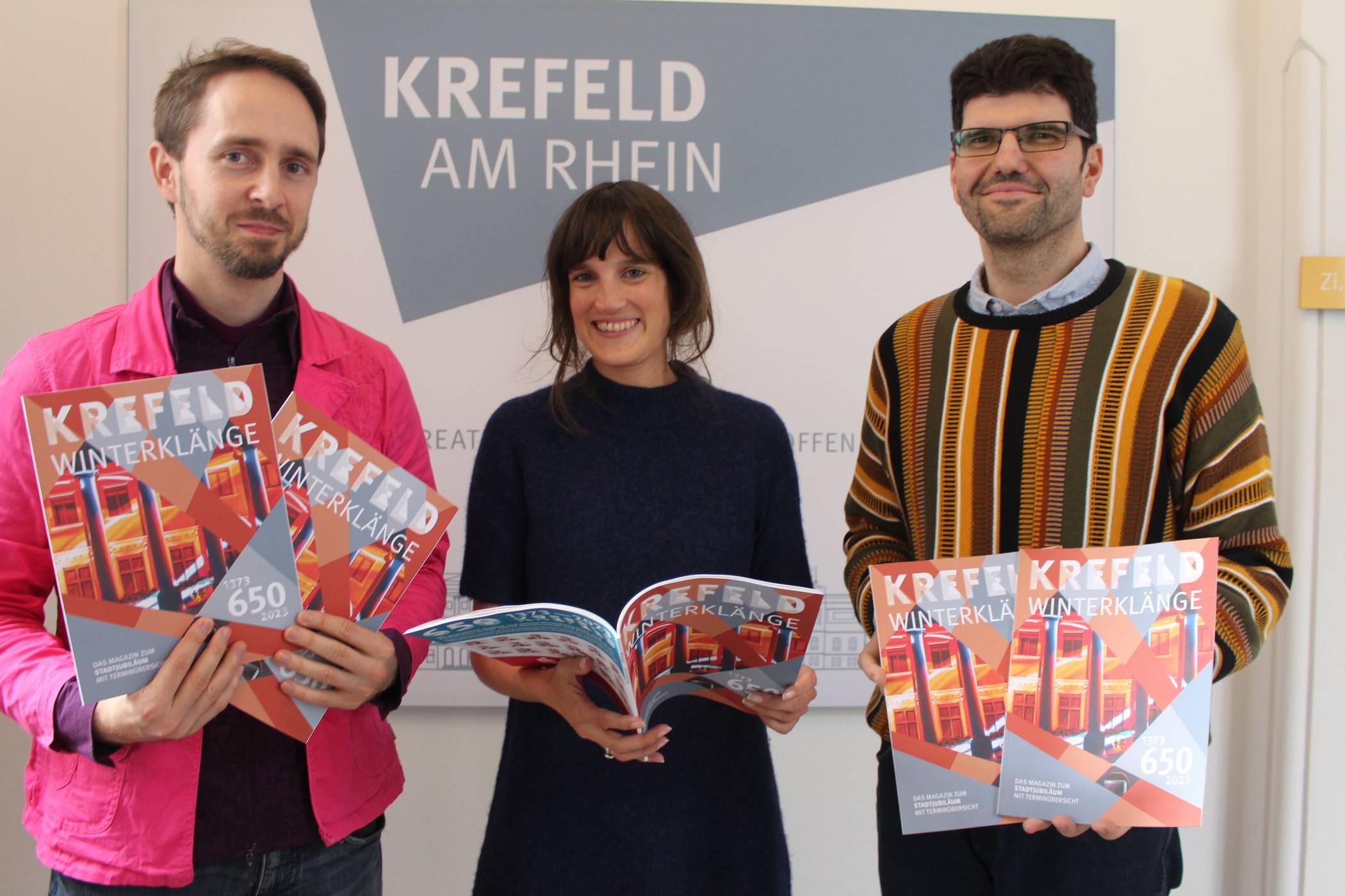 Stellen das Winterheft zum Stadtjubiläum vor: die Leiterin des Krefelder Marketingamtes Claire Neidhardt sowie die Musiker des Ensembles Crush, Lukas Tobiassen (l.) und Marin Petrov, die zu ihrem Mitmachprojekt für alle Bürger einladen.  Foto: Müller