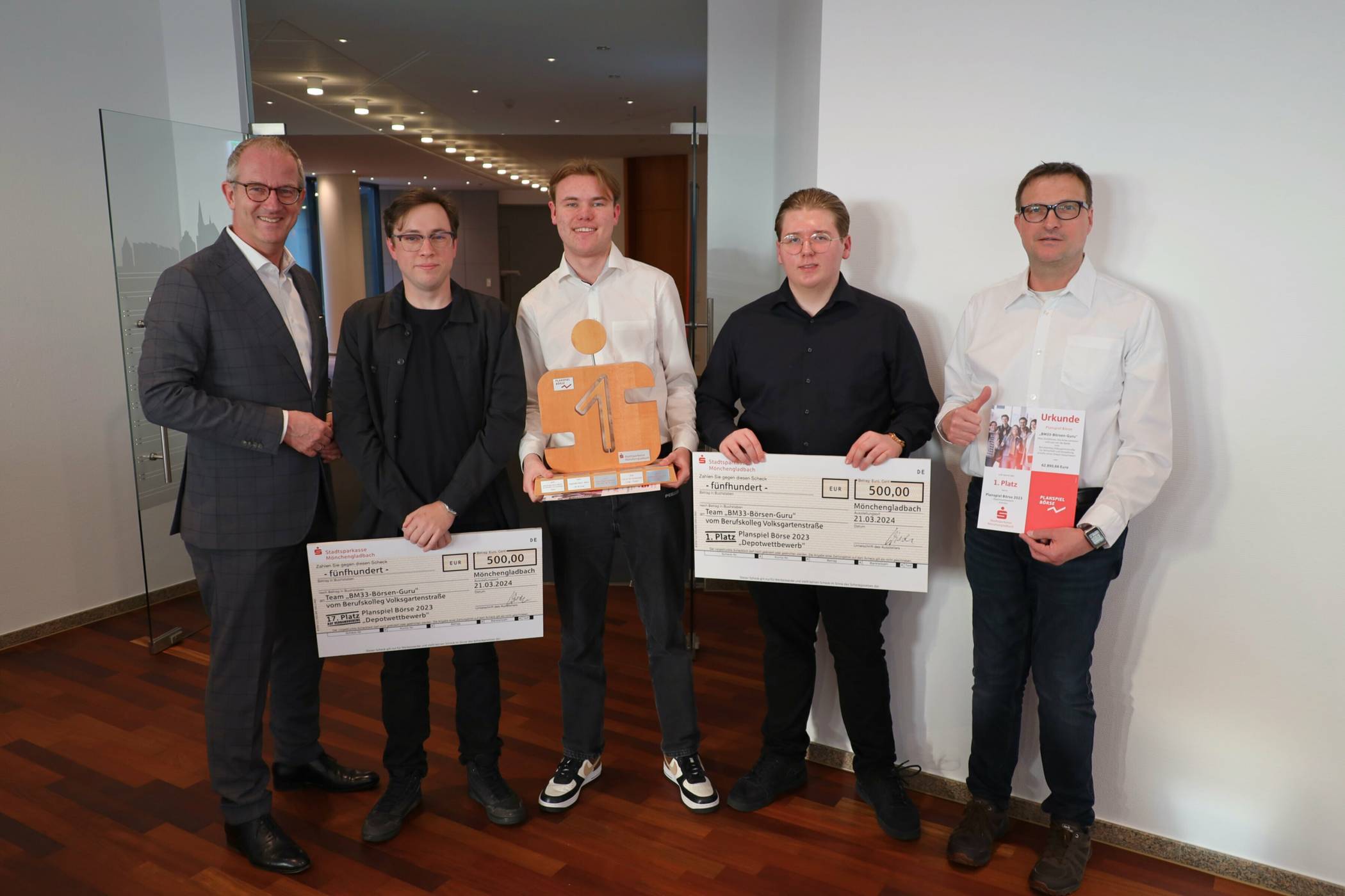 Sparkassendirektor Ralf Grewe mit dem Siegerteam BM33-Börsen-Guru vom Berufskolleg Volksgartenstraße, rechts Lehrer Matthias Kleine.   