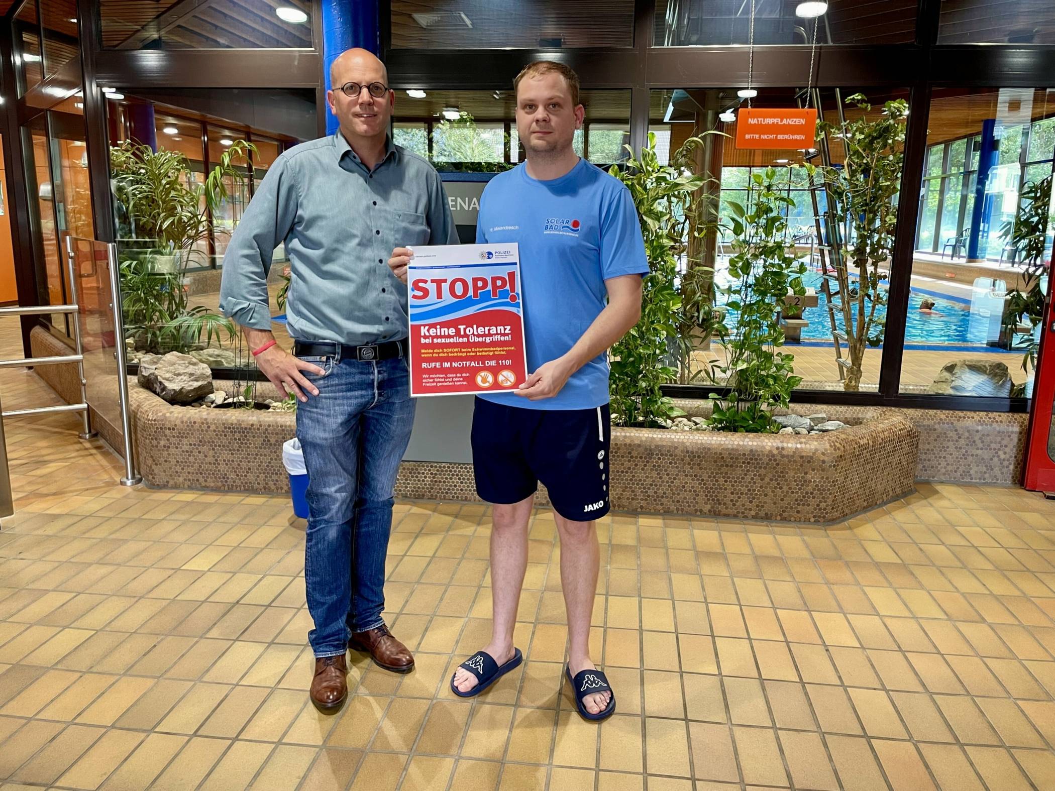 Dirk Lankes, Vorstand der Schwalmtalwerke (l.) und Thomas Meiendresch vom Solarbad zeigen ein Plakat, welches gut sichtbar aufgehängt wird.   