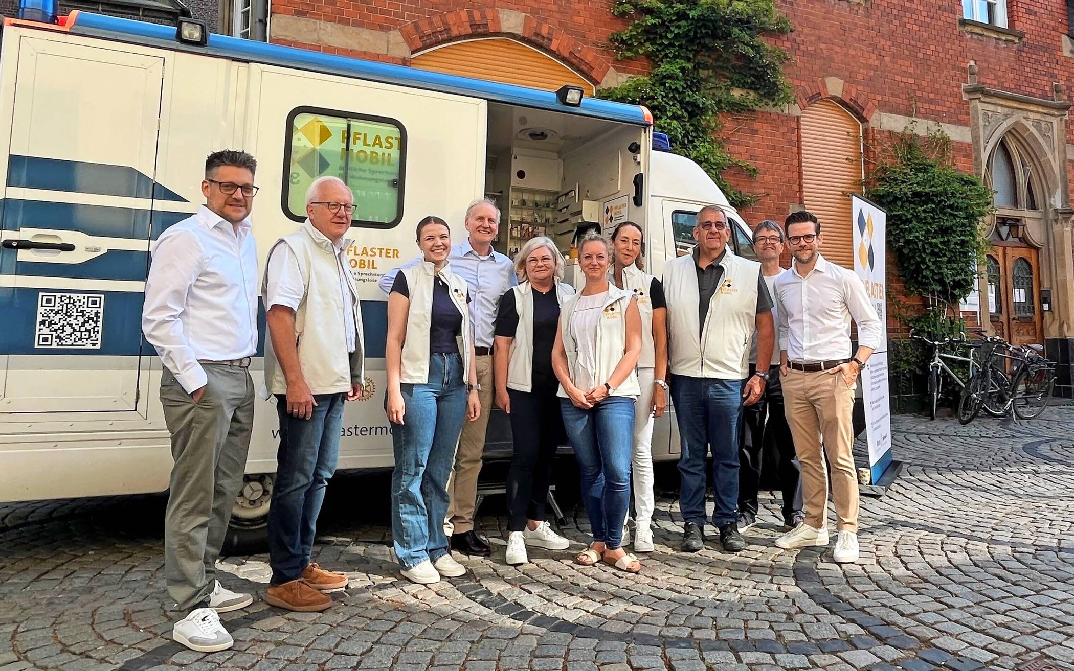 Sebastian Dreyer, Beigeordneter für Soziales, Jugend und Gesundheit (l.), und OB Felix Heinrichs (r.), mit einem Teil des ehrenamtlichen Pflastermobil-Teams. 