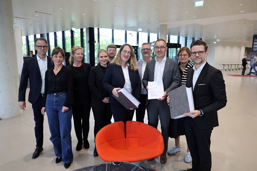 Nach nur vier Monaten konnte die Baugenehmigung überreicht werden. Daran haben u.a. mitgewirkt (v.l.): Alexander Vogel (Leiter NVR), Vera Tolo (Referentin des OB), Laetitia Cen und Tabea Oppolzer (sop Architekten), Bastian Dormels (Bauordnung), Claudia Schwan-Schmitz (Technische Beigeordnete), Philipp Klein und Thijs Storms (Bauordnung), Miriam ten Busch (Leiterin Bauordnung und Denkmalschutz) und OB Felix Heinrichs. 