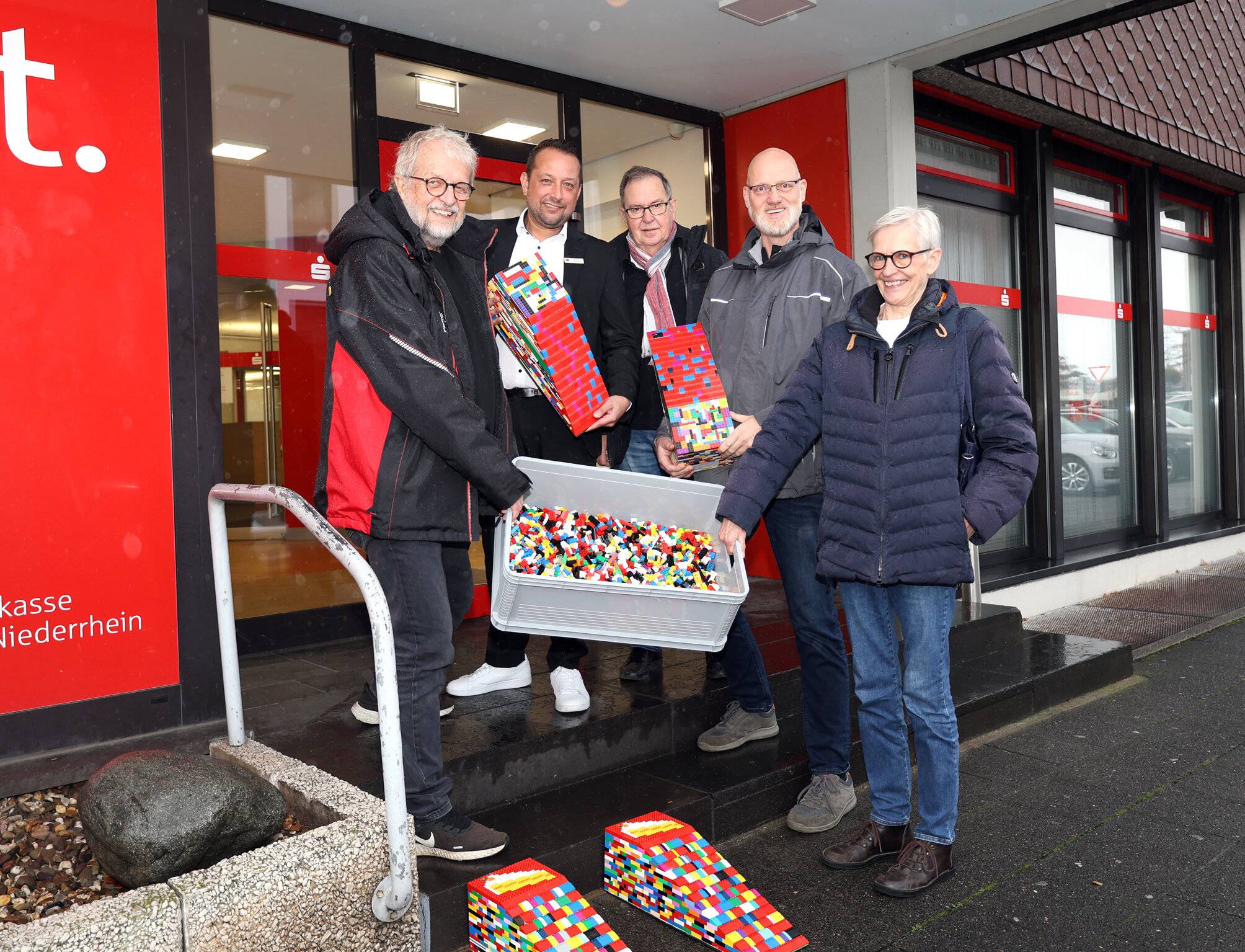 Der Verein „Repelen aktiv“, Ehrenamtliche des Moerser SCI und die Sparkasse am Niederrhein möchten so viele Repelener Geschäfte wie möglich mit bunten Baustein-Rampen barrierefrei machen (v.l.): Wolfgang Eisenmann, Markus Schürmann, Christian Birk, Pieter van der Meer und Elke Zacharias.
