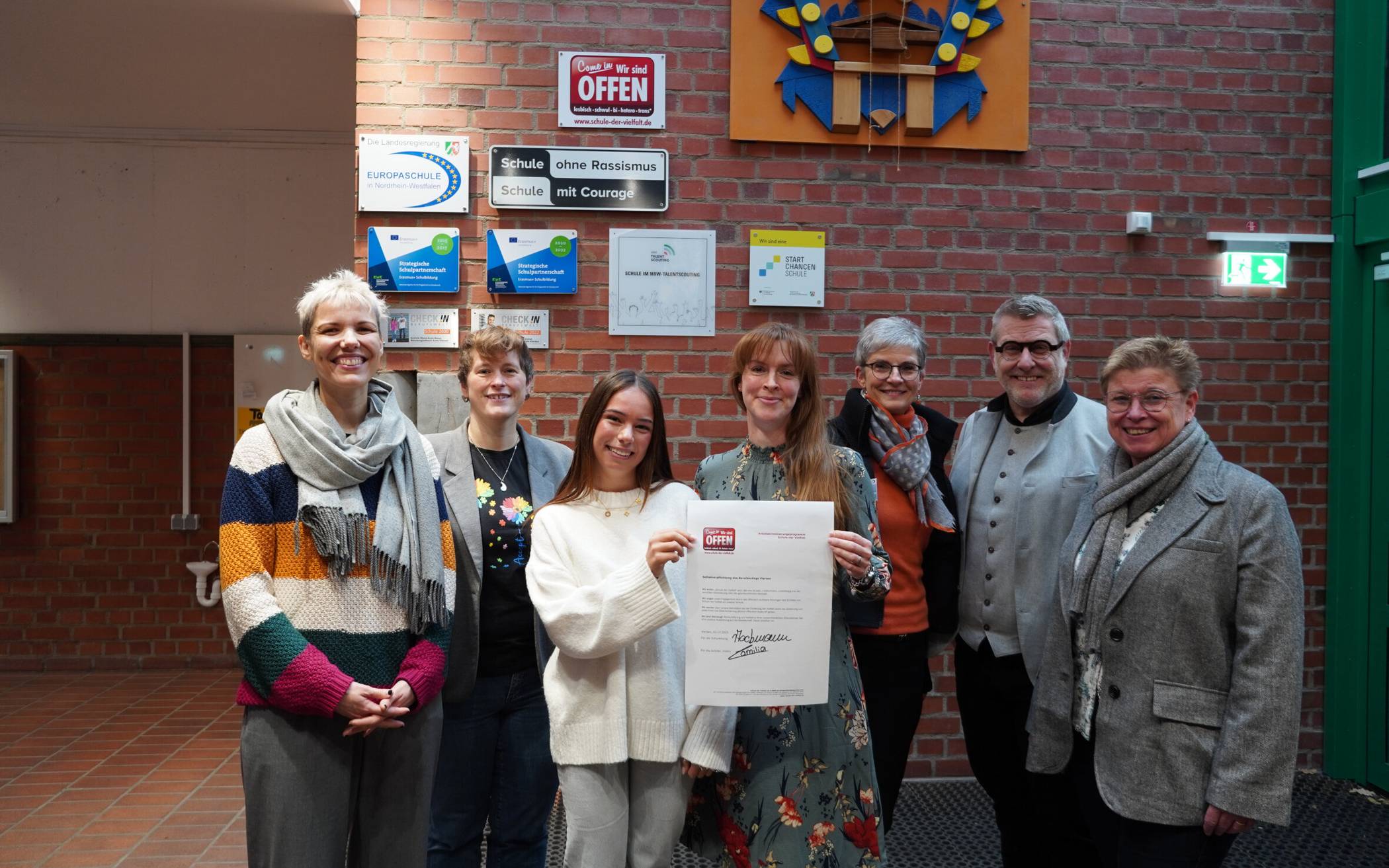  Freude vor der Plakette „Schule der Vielfalt“ im Berufskolleg Viersen mit der unterzeichneten Selbstverpflichtungserklärung. 