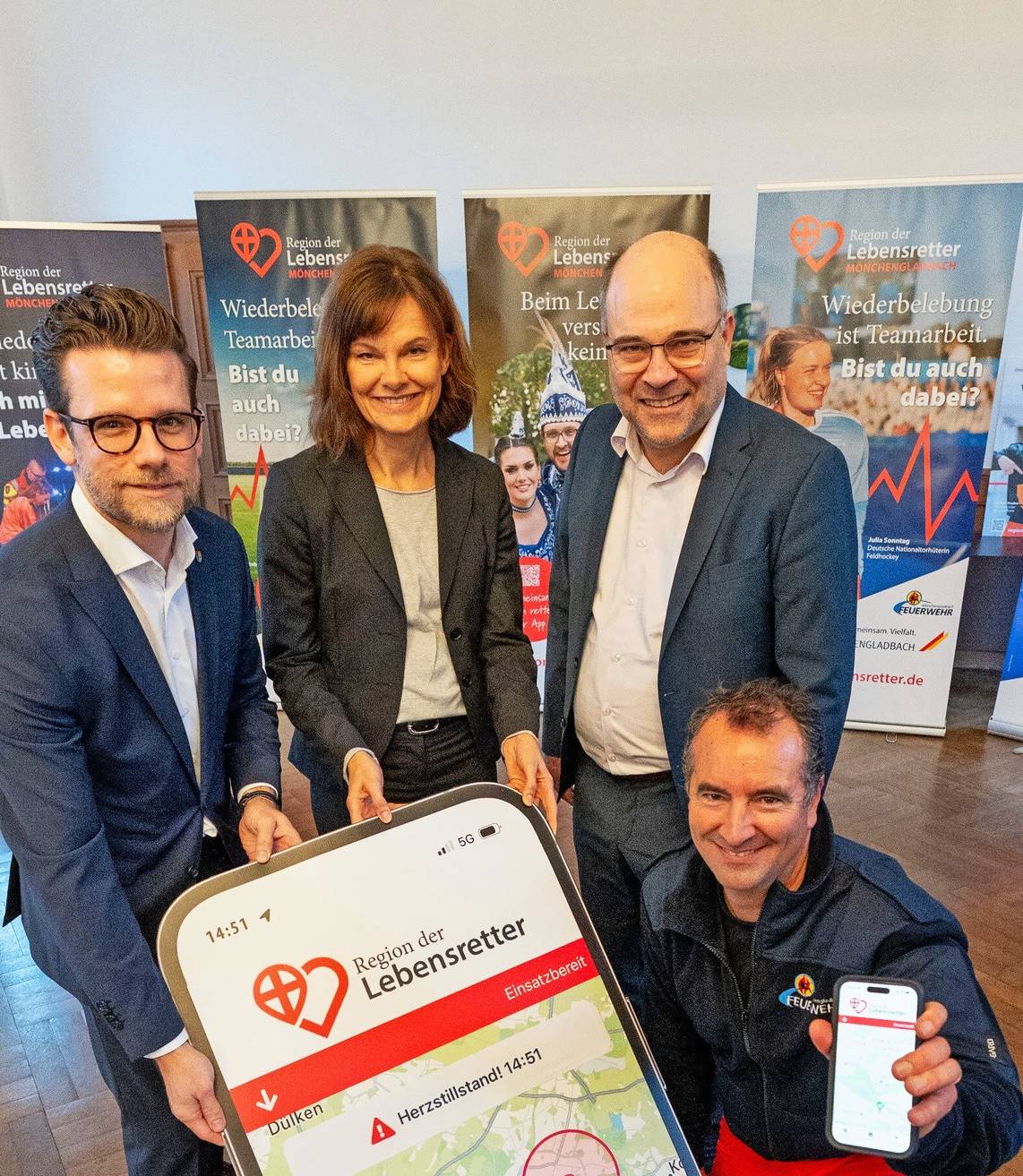„Im Ernstfall benachrichtigt die App bis zu vier Ersthelfer, die sich in der Umgebung befinden“: Oberbürgermeister Felix Heinrichs, die zuständige Beigeordnete Silke Wehmhörnern, Prof. Dr. Michael Müller, Vorsitzender des Vereins „Region der Lebensretter“, und Marc Deußen, Ärztlicher Leiter des Rettungsdienstes (v.l.), stellten die neue Ersthelfer-App vor.