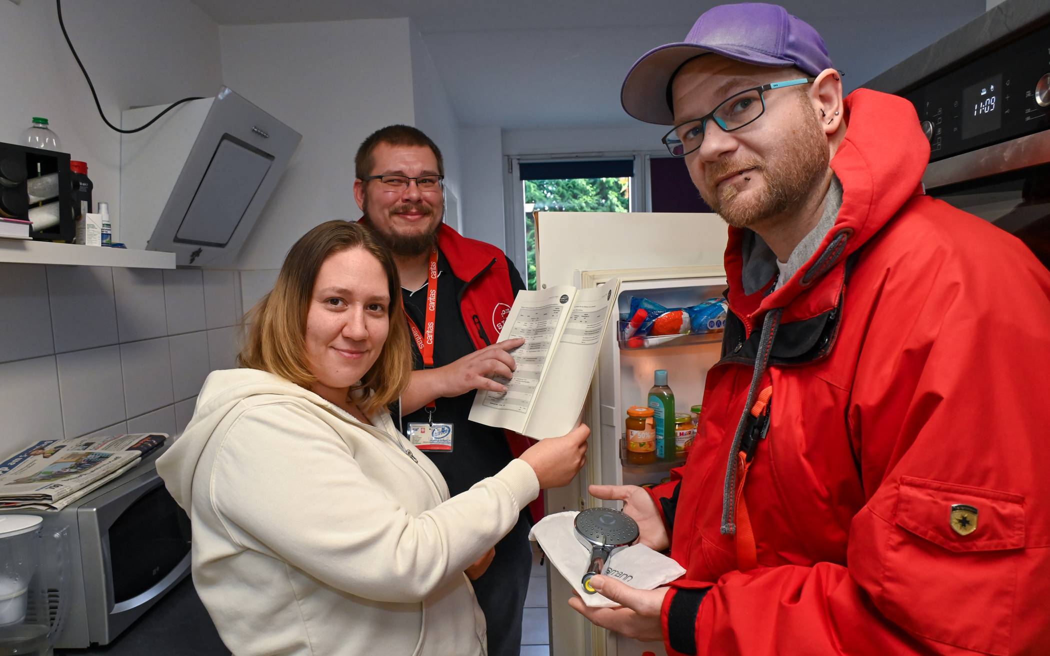  Wie viel Strom könnte Melina Wildschütz sparen, wenn sie ihren alten Kühlschrank austauschen würde? Die Caritas-Energieberater Tim Hofmeyer (Mitte) und Markus Jakobs rechnen es ihr anhand ihres zuvor durchgeführten Stromspar-Checks vor.  