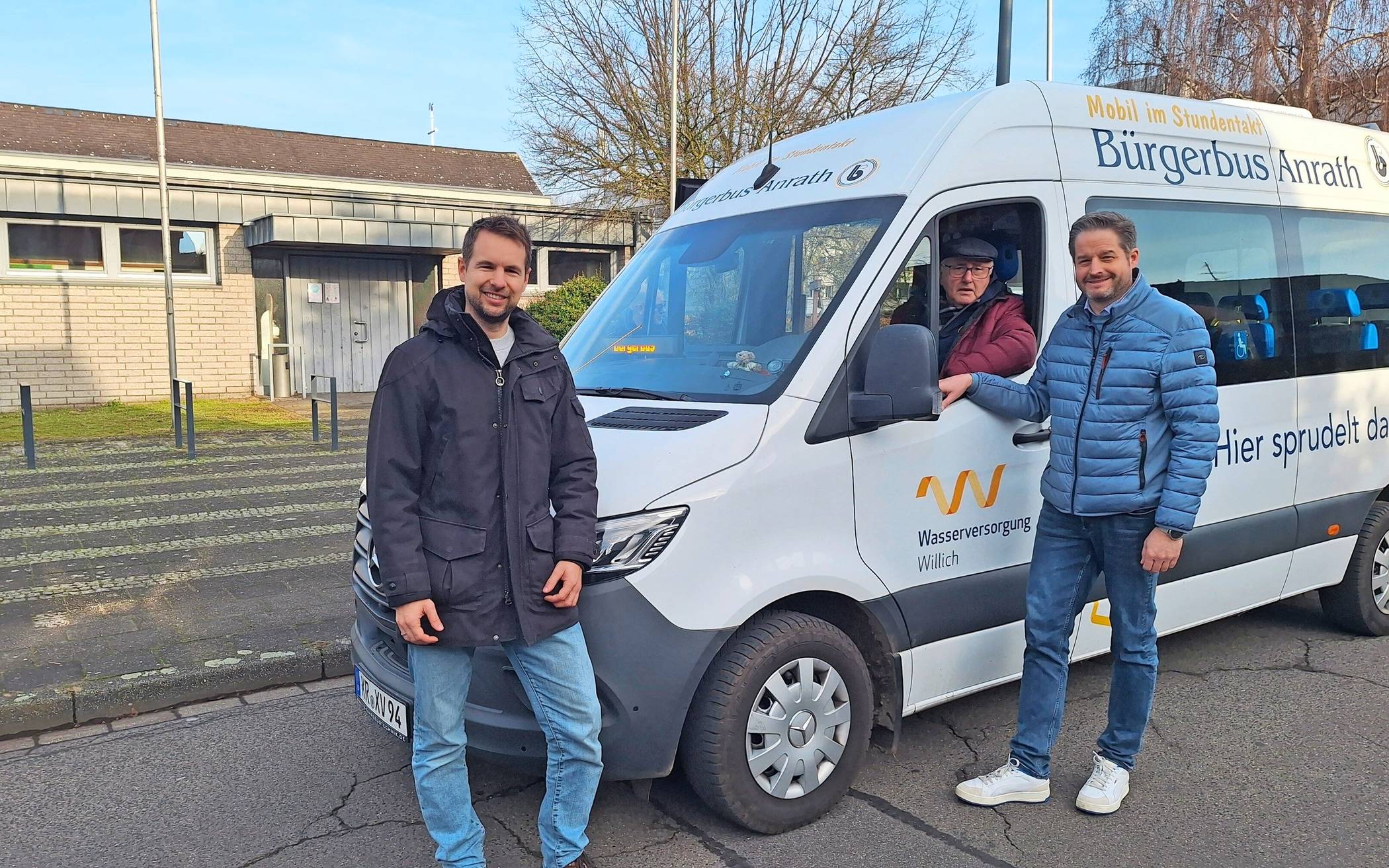 Vor dem Pfarrzentrum St. Pankratius in Bösinghoven lassen sich Bürgermeister Christian Bommers (r.) und Philipp Grüneberg, Vorsitzender des Bürgervereins Ossum-Bösinghoven, von Fahrer Albert Stauten den Bus des Bürgerbusvereins Anrath zeigen. In dem Willicher Stadtteil läuft das Projekt seit vielen Jahren erfolgreich. 