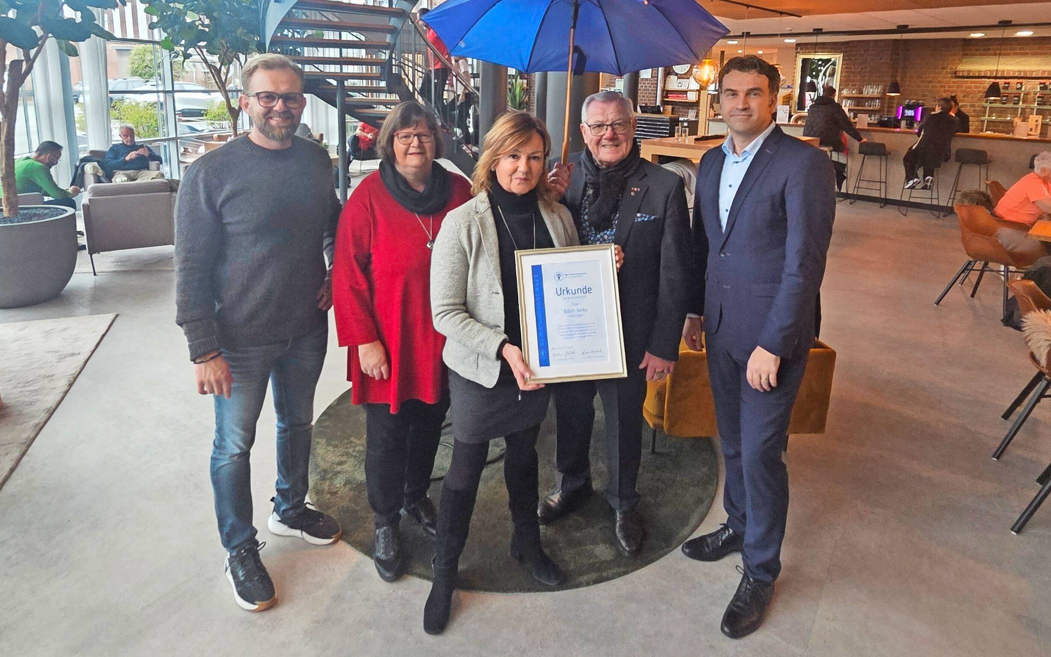 Übergabe der Schirmherrschaft beim Kinderschutzbund. Halle-22-Inhaberin Edith Gribs (Mitte) ist die Schirmherrin des Kinderschutzbundes für 2026. Die Urkunde wurde ihr von Barbara Jäschke (2. v. l.) und Dieter Lambertz (2. v. r.) vom Kinderschutzbund überreicht. Bei der Übergabe dabei Halle-22-Geschäftsführer Thomas Mathes (links) und der ehemalige Schirmherr Stadtwerke-Geschäftsführer Tafil Pufja.  