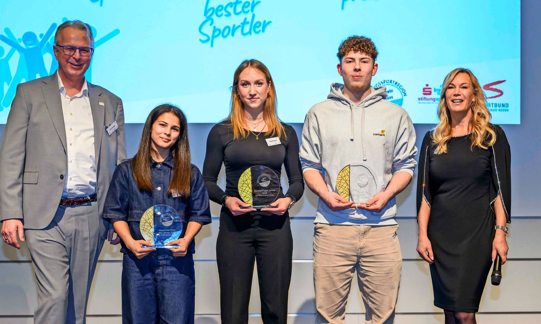 Kreisdirektor und Kreis-Sportdezernent Dirk Brügge mit (v.l.) mit Madina Bayramova (Newcomerpreis 2025), Sarah Dicks (Beste Sportlerin 2025), Fabian Mager (Bester Sportler 2025) und Moderatorin Birgit von Bentzel. 