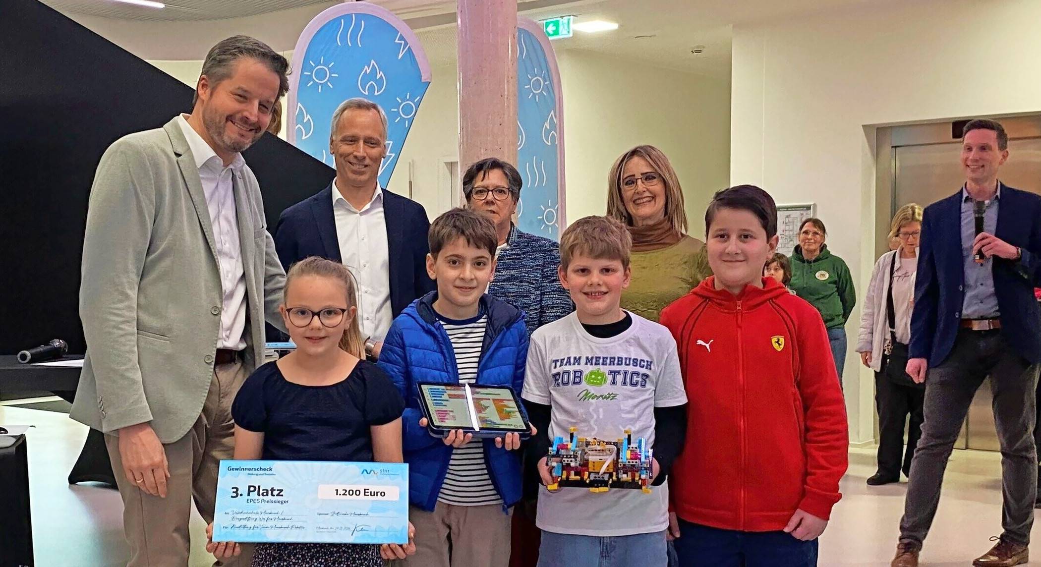  Das Team Meerbusch.Robotics freut sich über den dritten Platz beim Wettbewerb „Euer Projekt, Eure Stimme“. Vier Nachwuchstalente mit (v.l.) Bürgermeister Christian Bommers, Oliver Beyer, Birgit Schniewind, Béatrice Delassalle-Wischert und Daniel Wolter, Technischer Leiter der Stadtwerke Service Meerbusch Willich GmbH &amp; Ko. KG. 