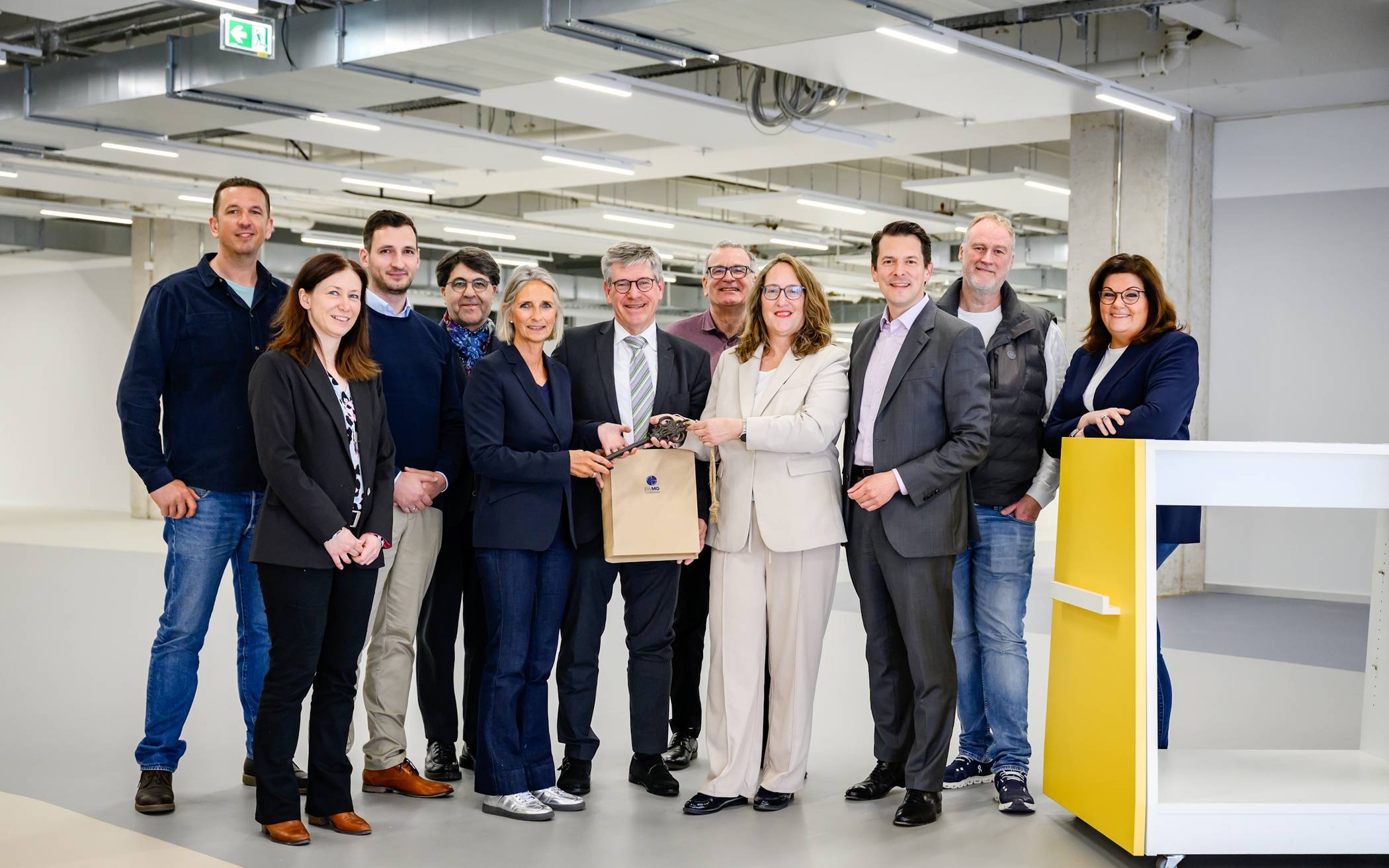 Schlüsselübergabe in den noch leeren neuen Räumen der Bibliothek: (v. l.) Peter Thomassen (Gebäudemanagement), Katja Becker-Lis (Betriebsleiterin Gebäudemanagement), Friedrich Idt (Gebäudemanagement), Yilmaz Holtz-Ersahin (Fachbereichsleiter Bibliothek und Archiv), Christiane Schüßler (Beigeordnete für Bildung, Kultur, Sport), Dr. Ulrich Schückhaus (Vorsitzender der EWMG-Geschäftsführung), Arno van Rijn (Leiter Stadtteilbibliothek Rheydt), Claudia Schwan-Schmitz (Technische Beigeordnete und EWMG-Geschäftsführerin), Stefan Anspach (EWMG-Geschäftsführer), Michael Kremer (EWMG), Kerstin Schaaf (EWMG-Prokuristin und -Geschäftsbereichsleiterin).  