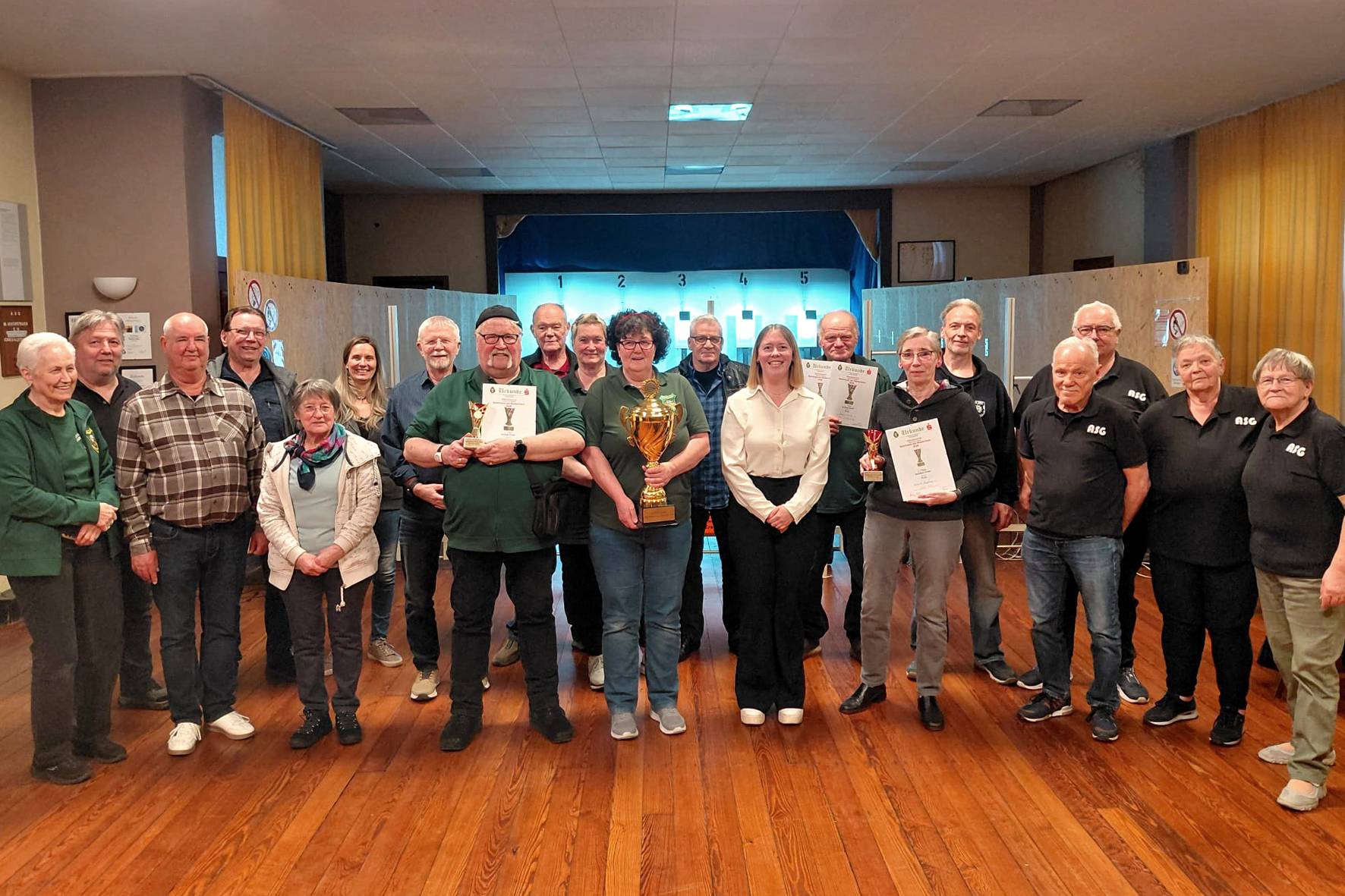 Sparkassenmitarbeiterin Dana Göntgen (weiße Bluse) überreichte den großen Mannschaftspokal an Klaudia Jung. Deren Ehemann Udo (links daneben) wurde als bester Einzelschütze geehrt. Bei den Damen gewann Hildegard Waggeling von den Moerser Polizei-Sportschützen (rechts mit Urkunde). Über einen rundum gelungenen Schießwettkampf freuten sich Schießwart Uwe Baumeister (2.v.l.), Vorsitzender Werner Steffen (daneben) sowie v.r.n.l.: Dagmar Baumeister, Petra Becker, Geschäftsführer Jürgen Becker und Uwe Bartels (alle vom Ausrichter ASG).