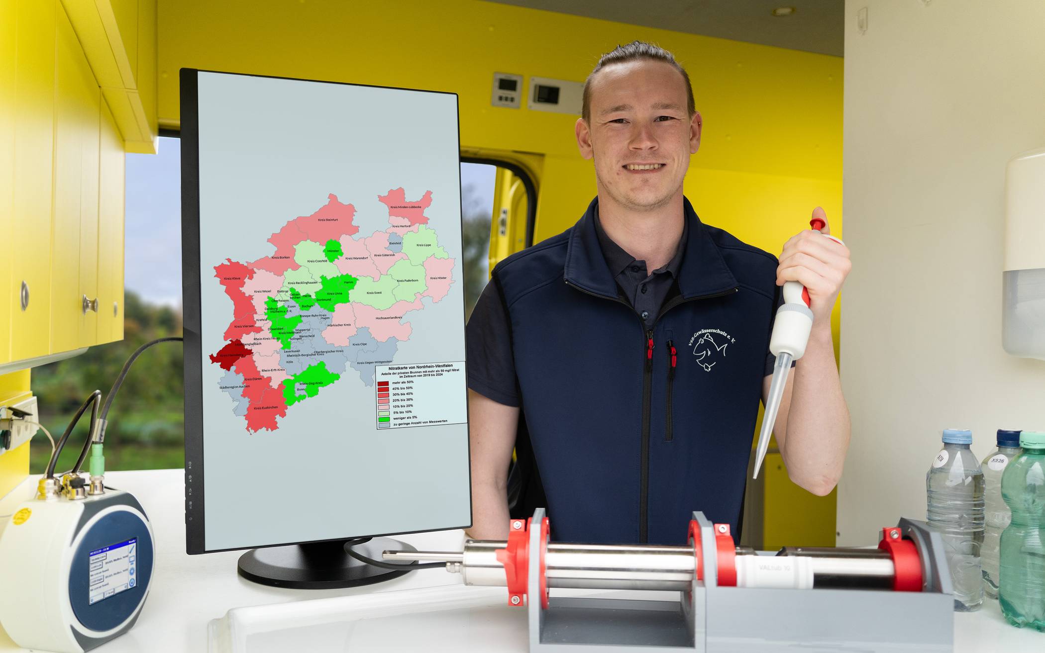 Milan Toups untersucht eine Brunnenwasserprobe, mit Nitratkarte von NRW im Labormobil vom VSR-Gewässerschutz 
