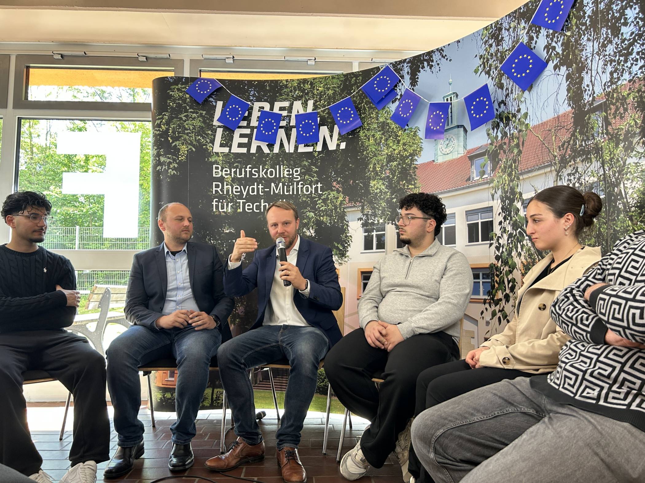  Schülerinnen und Schüler des Berufskollegs Rheydt-Mülfort für Technik diskutieren mit dem Europaabgeordneten Daniel Freund (Mitte). 