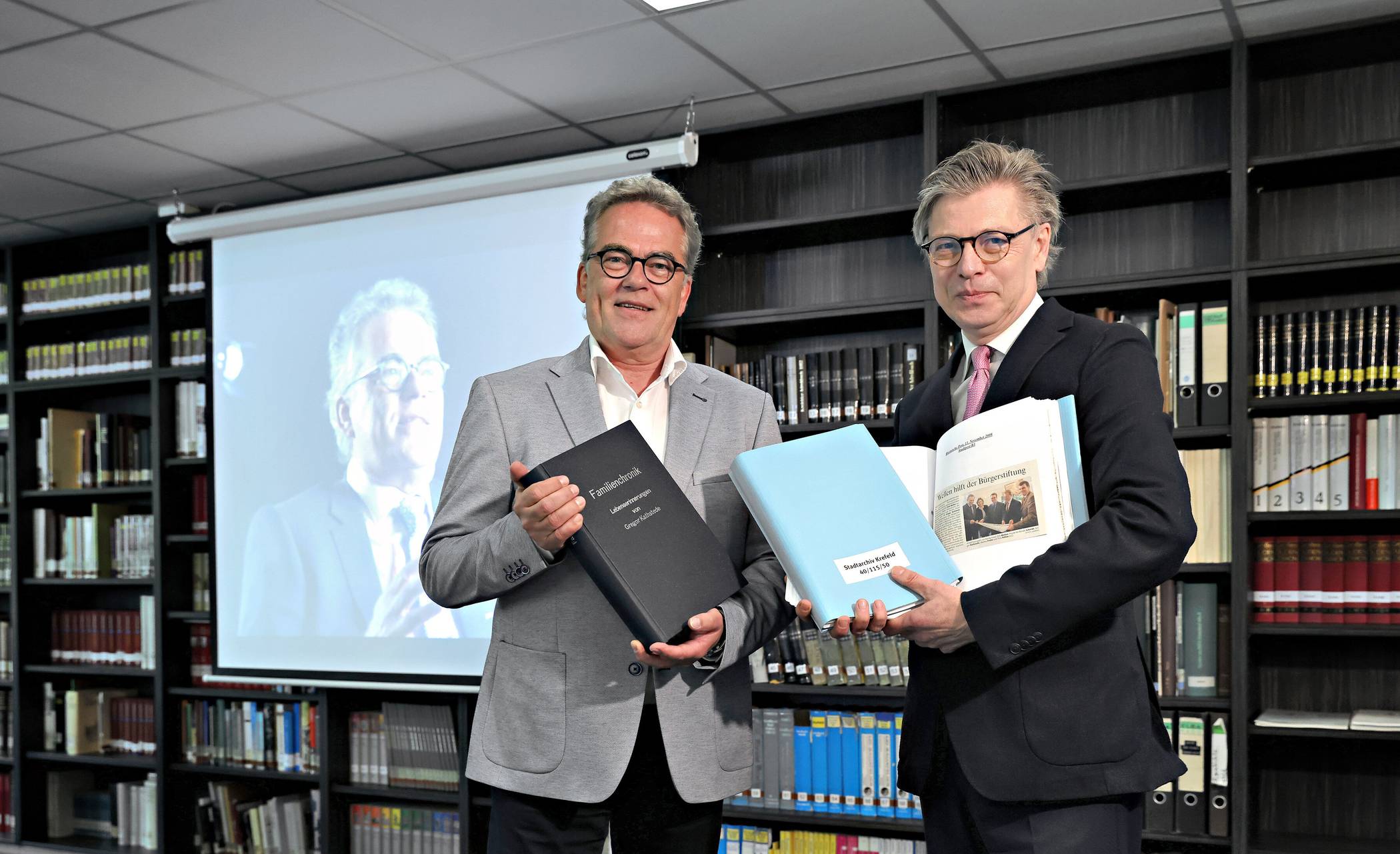Der ehemalige Krefelder Oberbürgermeister Gregor Kathstede (links) und Dr. Olaf Richter, Leiter des Stadtarchivs Krefeld, bei der Übergabe von Dokumenten und Unterlagen. Foto: Stadt Krefeld, Dirk Jochmann