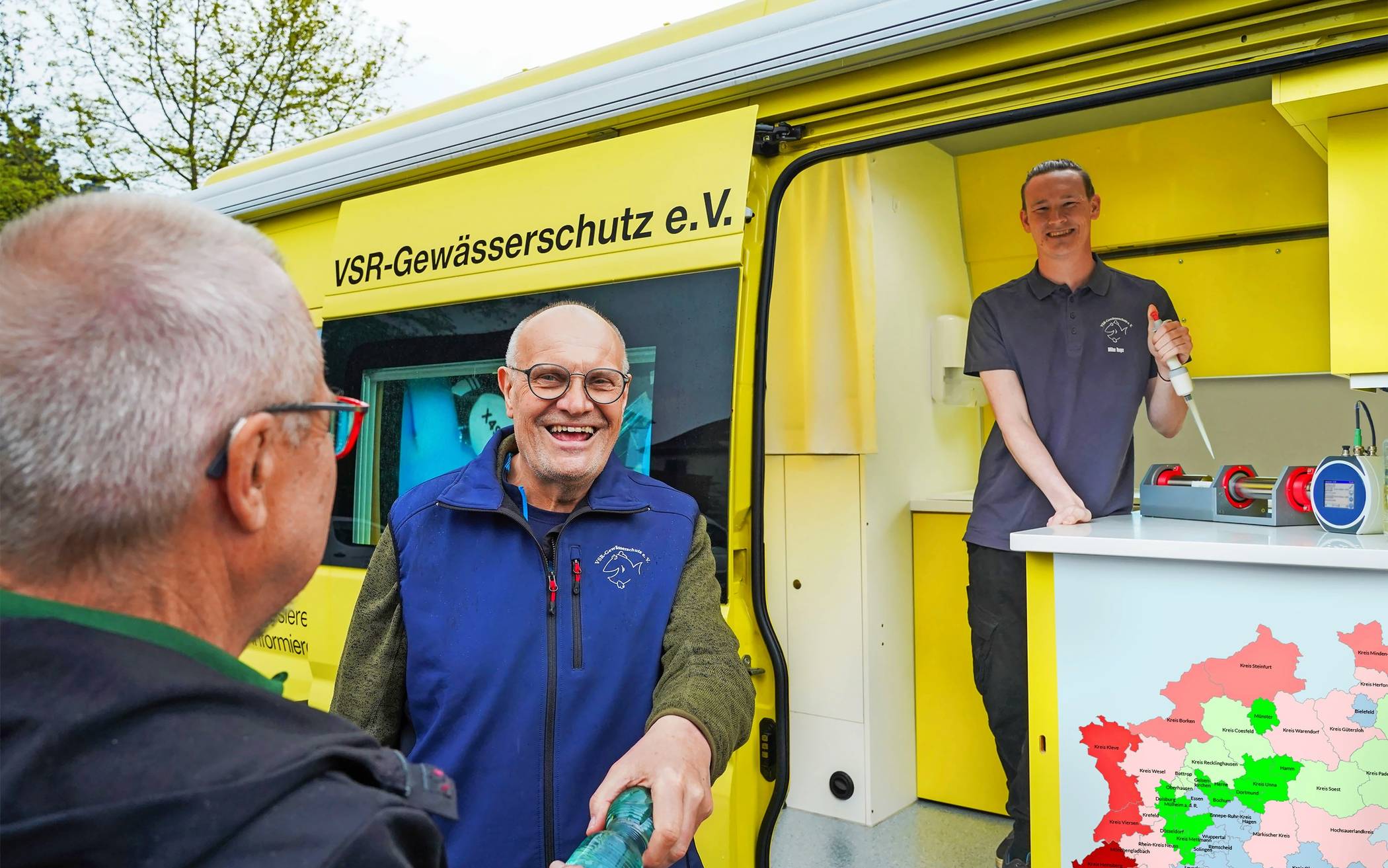 Dieter Knetsch(mitte) und Milan Toups (rechts) beraten einen Brunnenbesitzer und untersuchen eine Brunnenwasserprobe.  
