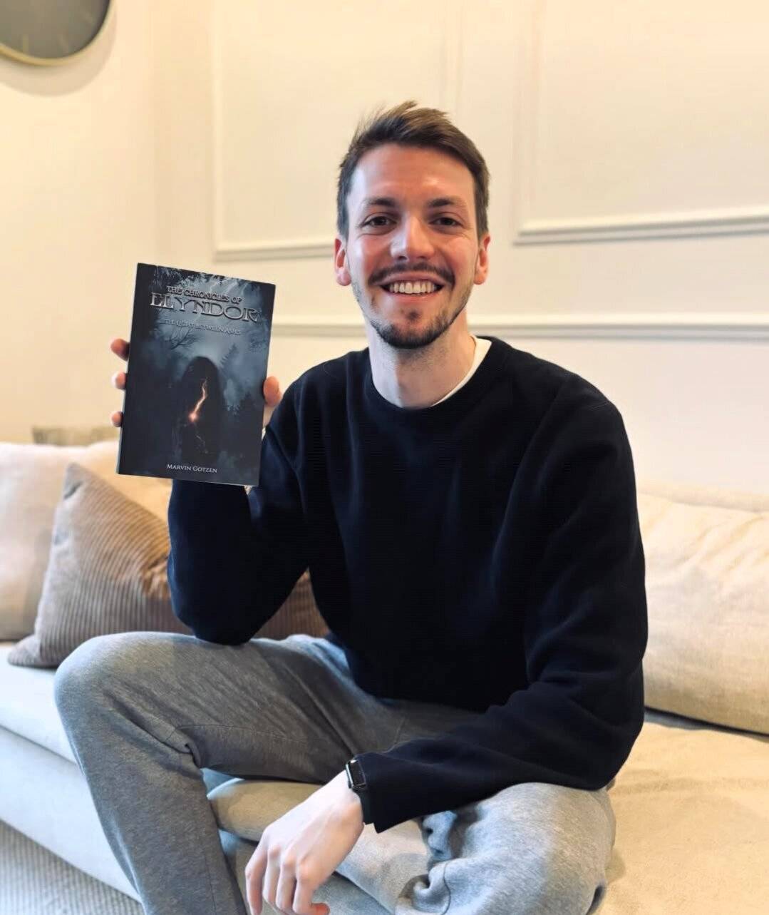 Marvin Gotzen mit einem Exemplar seines Romans „The Chronicles Of Elyndor - The Light Between Ashes“.   