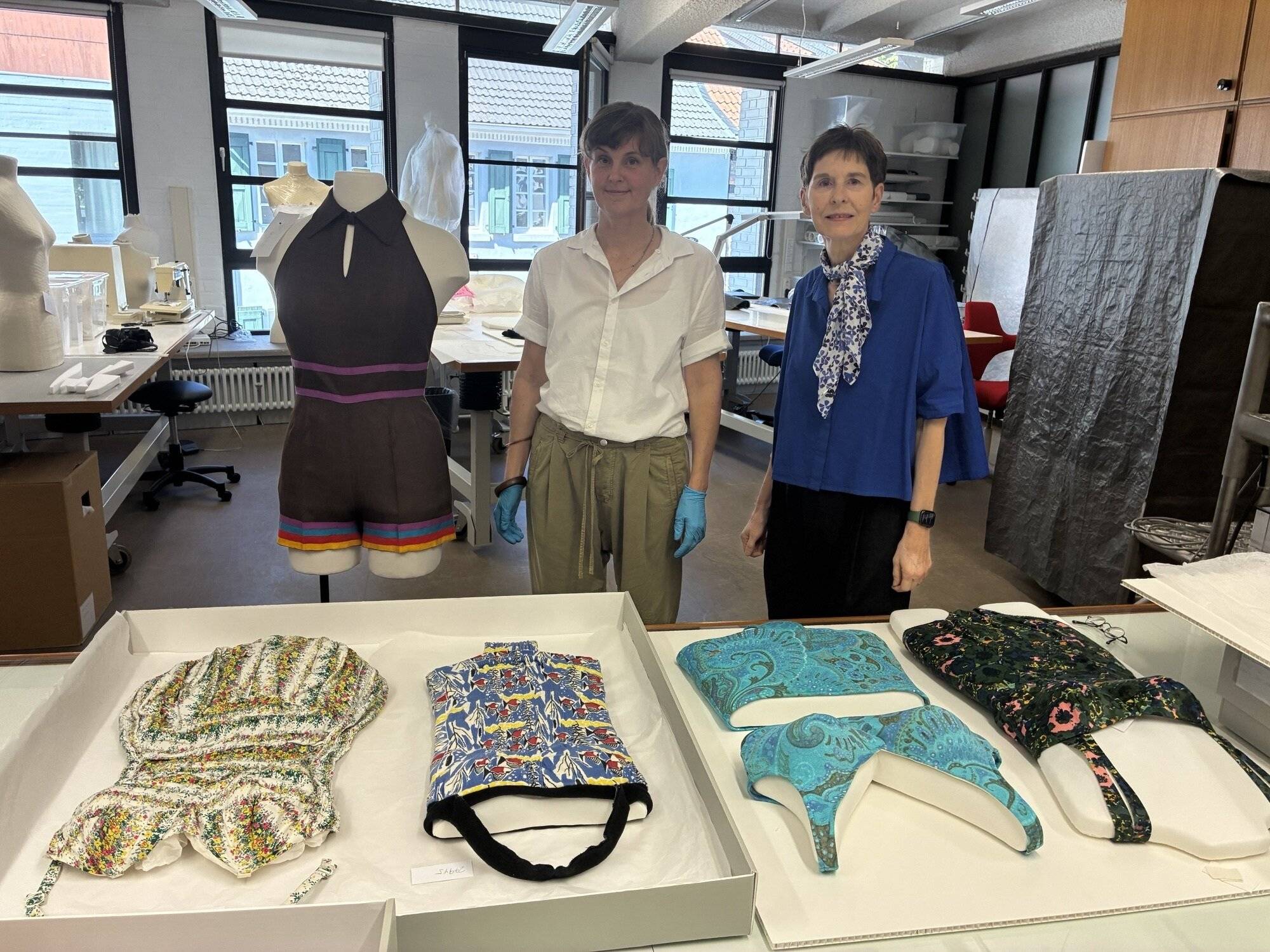  Badeanzüge der 50er und 60er Jahre auf dem Tisch: Restauratorin Katja Wagner (l.) hat sie aufbereitet, Kuratorin Dr. Isa Fleischmann-Heck nimmt sie in ihre Ausstellung im Frühjahr 2027 auf.   