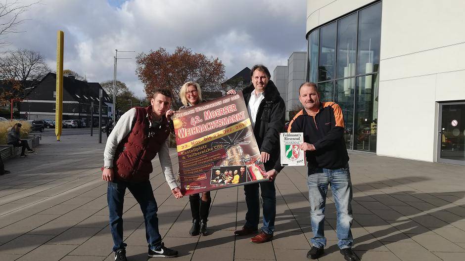 Schausteller Toni (l) und Sven (r) Feldmann sowie Sabine Opgen-Rhein und Michael Birr von MoersMarketing freuen sich auf den Moerser Weihnachtsmarkt.
