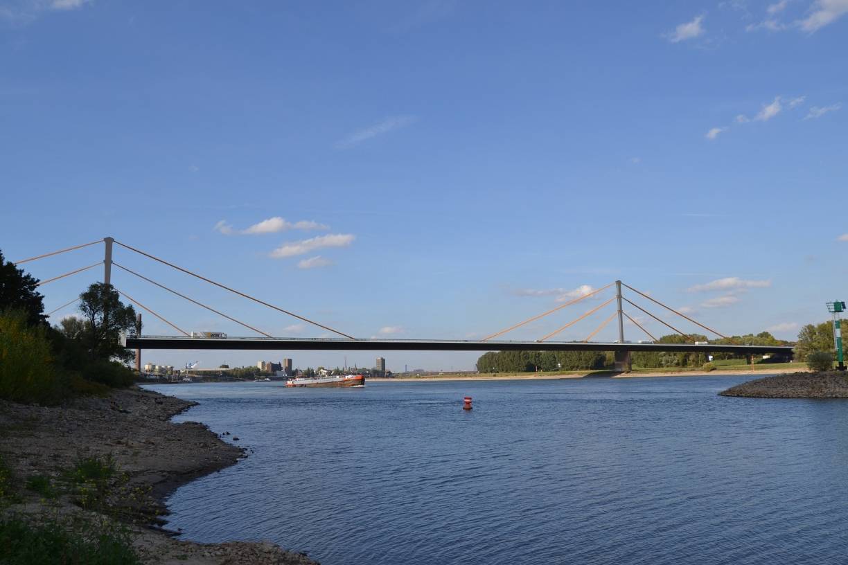 Die marode A40-Rheinbrücke zwischen Duisburg-Homberg und Duisburg-Neuenkamp wird bis 2026 vollständig durch einen Neubau ersetzt. Fortlaufend werden Erhaltungsreparaturen durchgeführt und eine Wiege- und Sperranlage soll künftig übergewichtige Lkw ableiten.