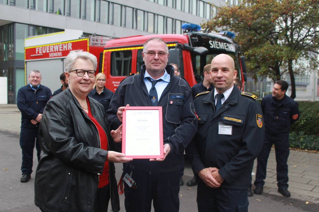 Würdiger Moment: Stadtdirektorin Beate Zielke und Feuerwehrchef Andreas Klos (r.) überreichen die Urkunde zur Zertifizierung der Betriebsfeuerwehr Siemens an deren Leiter Ulrich Dell (Mitte).Foto: Müller