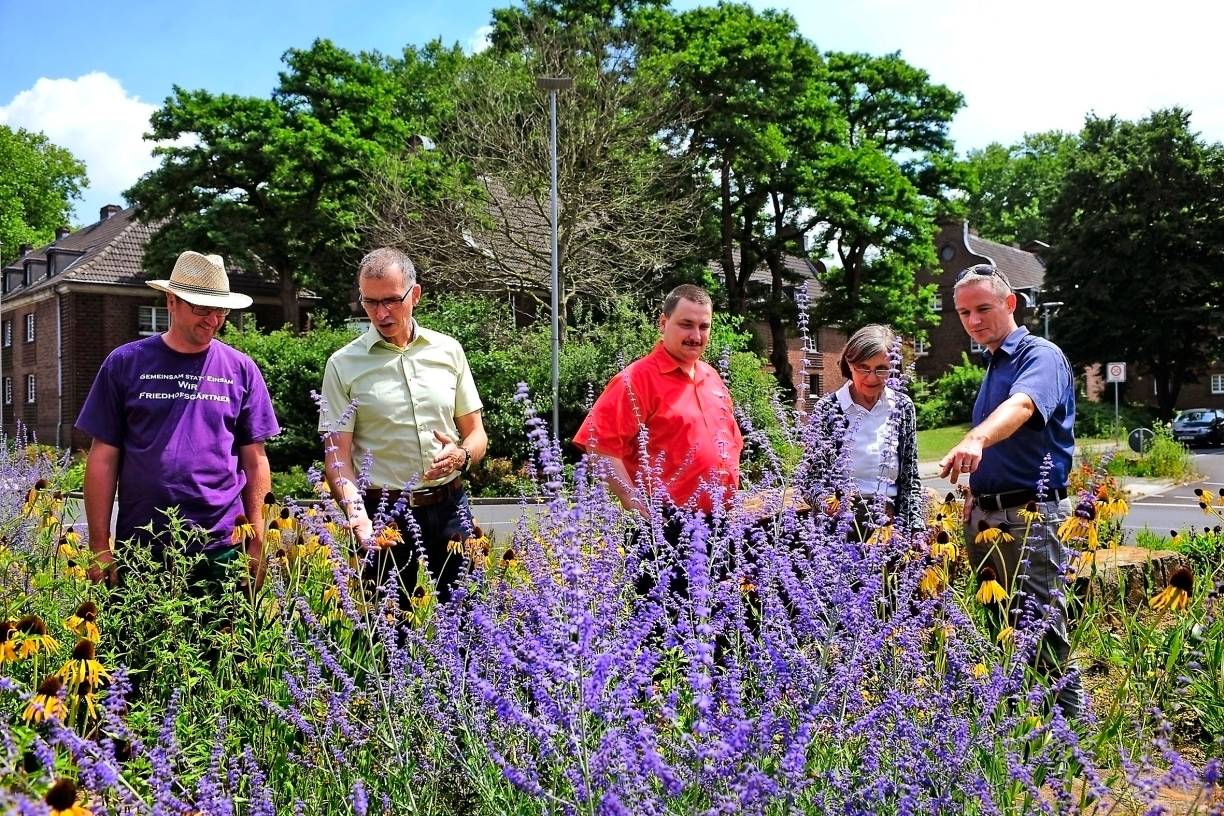  Der Kreisverkehr Bendschenweg/Fritz-Baum-Allee geht mit gutem Beispiel voran: Torsten Stückert (Friedhofsgärtnerei Torsten Stückert), Thomas Ketelaers (Raiffeisenmarkt Niep), Dirk Heisters (Toom Baumarkt Neukirchen-Vluyn), Marion May-Hacker (Agendabeauftragte Stadt NV) und Frank Grusen (Stadtmarketing) präsentieren die Wettbewerbsidee in blühender Umgebung. 
