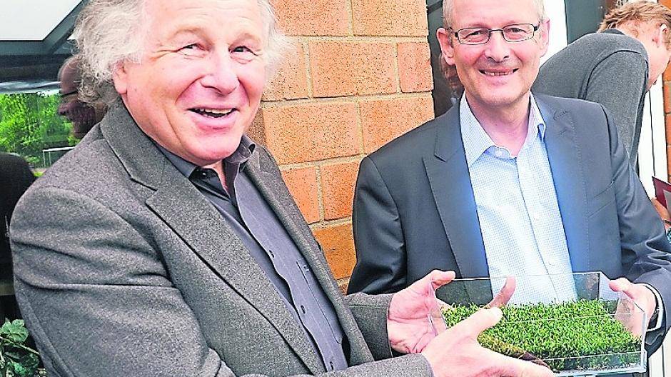 Projektleiter Harald Arndt (links) überreicht dem 1. Vorsitzenden Wolfgang Güdden ein erstes Stück Kunstrasen.