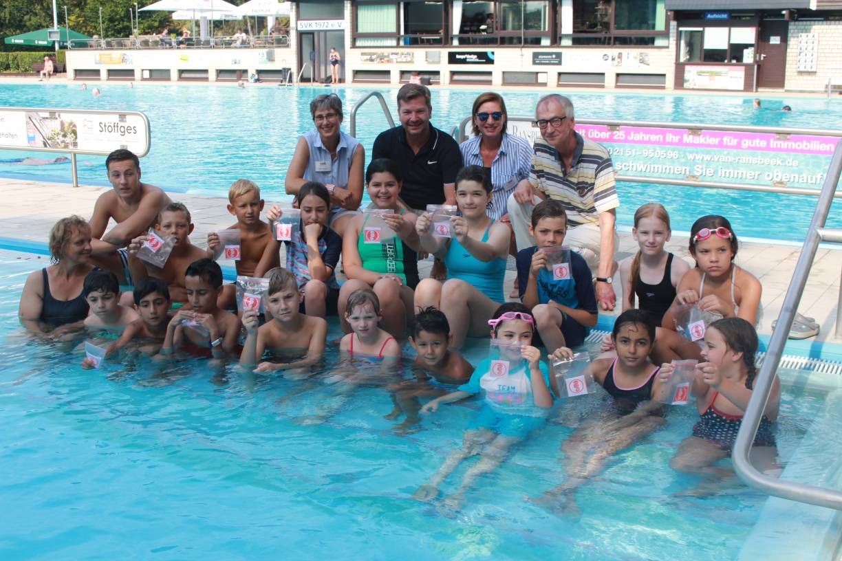 Geschafft: Die pfiffigen Kinder des Schwimmkursus halten für den Fotografen mit Stolz ihre Abzeichen hoch. Die meisten haben den Schwimmernachweis „Seepferdchen“ erworben. Darüber freuen sich auch die „Paten“ der Aktion: Sigrid Augustin (l.) und Monika Klingen (3.v.l.) von der Bürgerstiftung, Michael Kreis (2.v.l.) von Intersport Borgmann und SVK-Vereinsvorsitzender Werner Gottschalk (r.). Trainerin der Kinder ist Nicole Hoppe (unten l.) mit Assistent Mika.