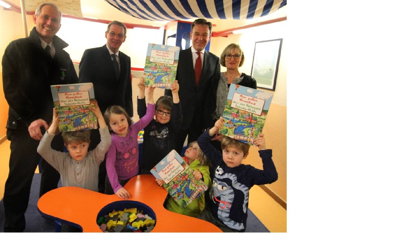 Fynn, Charlotte, Justus, Ida und Henri aus dem Kindergarten Hoppetosse zeigen ihre neuen Wimmelbücher. Naturpark-Verbandsvorsteher Peter Ottmann (2.v.l), Naturpark-Geschäftsführer Michael Puschmann (l.) sowie Sparkassen-Vorstand Lothar Birnbrich (2.v.r.) überreichten der Hoppetosse-Leiterin Angela Haller die ersten Exemplare.