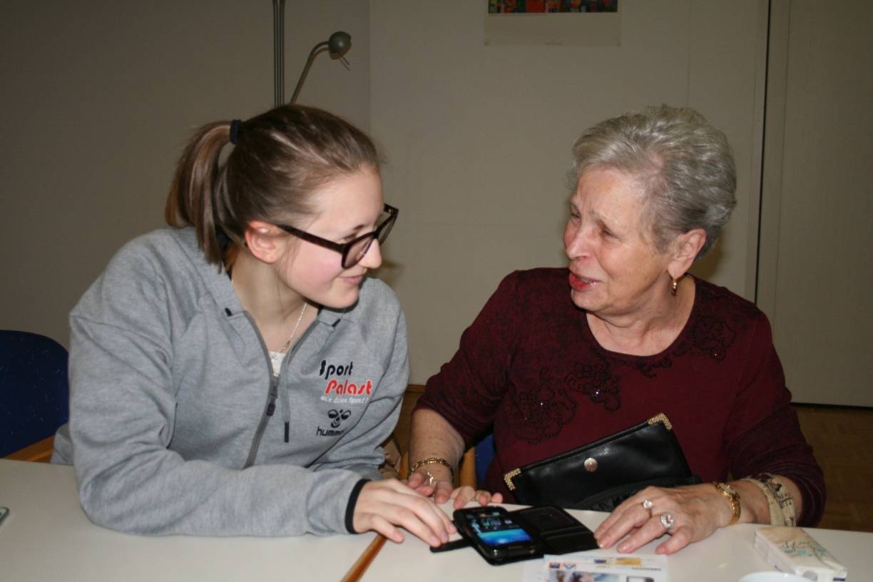 Yvonne Kallisch macht das neue Smartphone von Gerda Pieper startklar.
