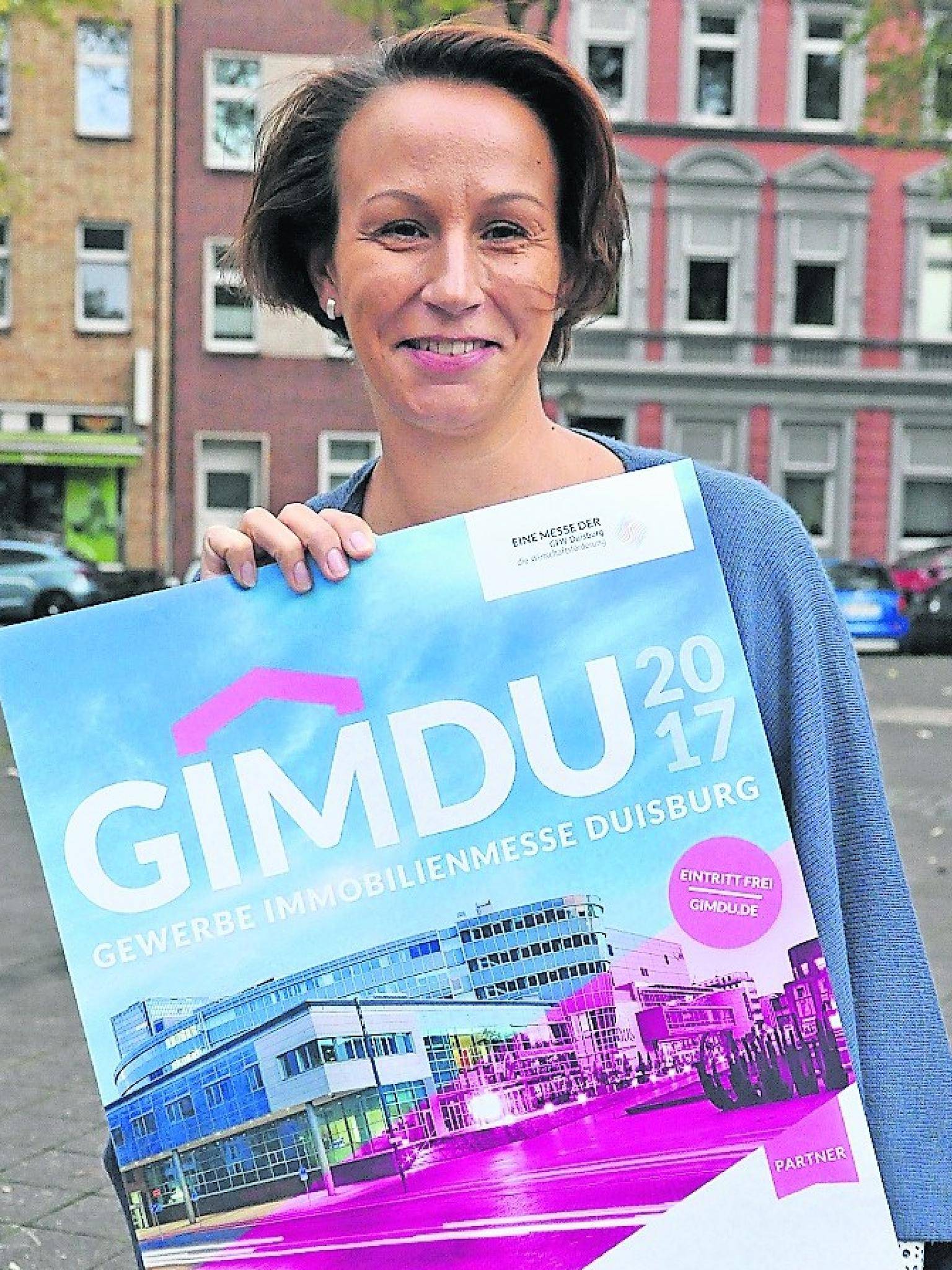 Manuela Kaminski präsentiert das Plakat der diesjährigen „GIMDU“ — der Duisburger Gewerbeimmobilien messe, die am 8. und 9. November im CityPalais stattfinden wird.