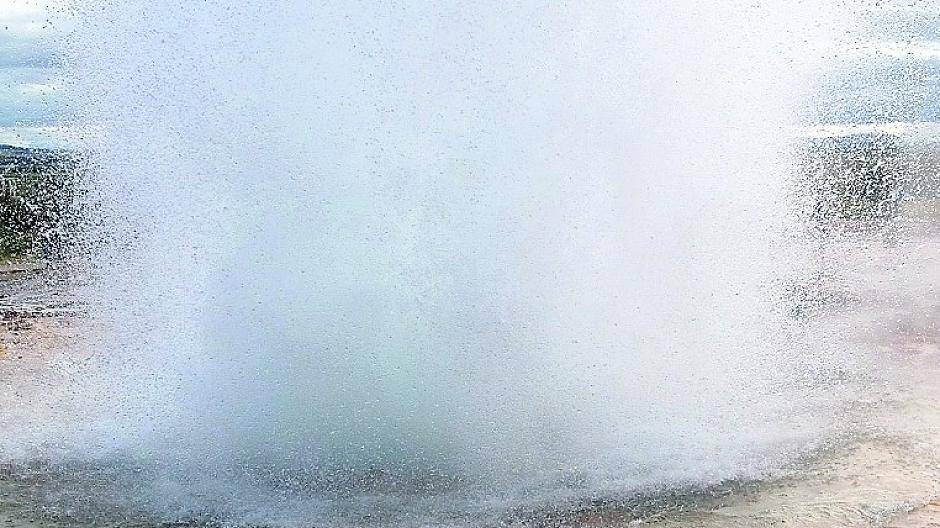 Zuverlässig alle acht bis zehn Minuten bricht der Geysir Strokkur im Geothermalgebiet Haukadalur in einer riesigen Fontäne aus, sehr zur Freude der umstehenden Touristen.