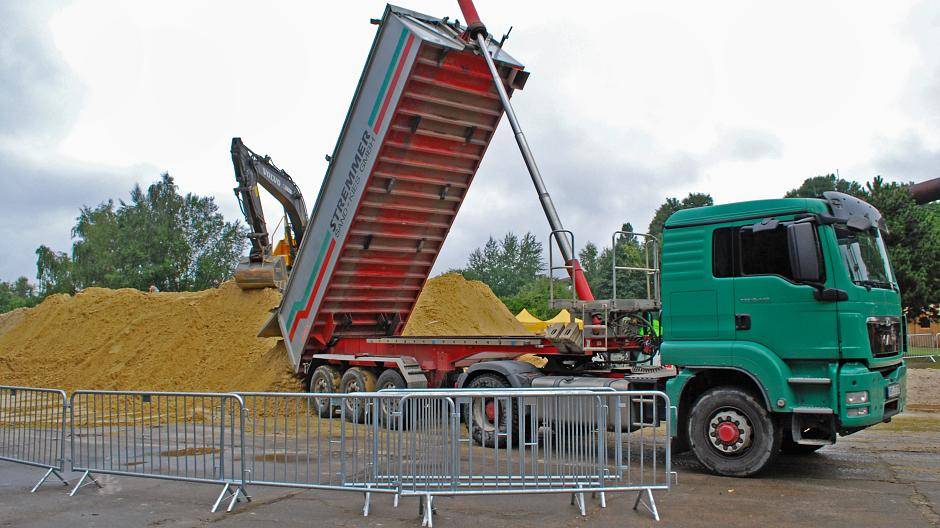 Bagger und Laster bringen Sand
