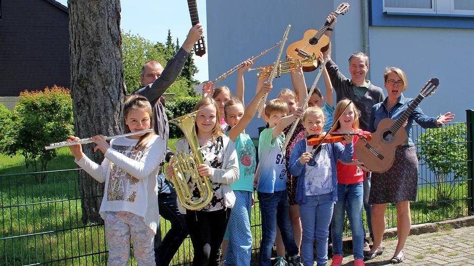  An der Eschenburgschule in Asberg freuen sich die ersten Schüler gemeinsam mit Musikschulleiter Georg Kresimon (r.), Stellvertreterin Ulrike Schweinfurth und Gitarrenlehrer Ralf auf der Heiden über die kostenlosen Leihinstrumente. 