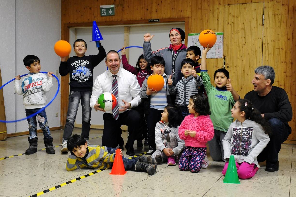  Guido Lohmann, Initiator und Motor von „Bewegen hilft“ e. V. mit der Turngruppe der Flüchtlingskinder, in der Mitte die Trainerin und Sportlehrerin Nabilla Hussein, rechts Nidal Hussein von der Grafschafter Diakonie. 