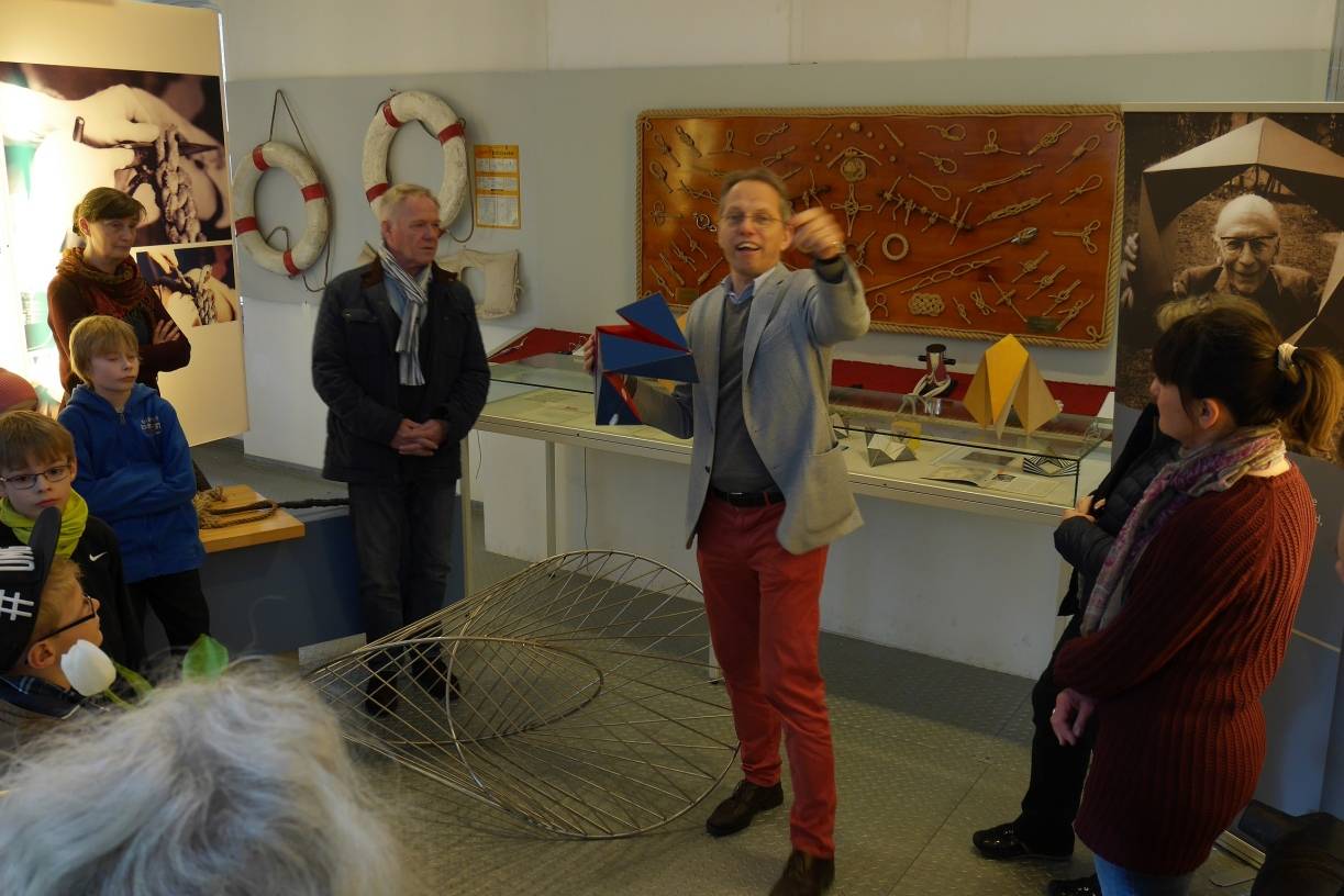 Anschaulich erklärt Tobias Langscheid die Zerlegung des Würfels in drei Teile, von denen einer aus einer Kette von sechs unregelmäßigen Tetraedern besteht, die sich komplett umstülpen lässt. Bei der Beobachtung des Weges, den die Raumdiagonalen des Würfels beim Umstülpen machen, entdeckte Paul Schatz den Oloid, wie er grafisch-plastisch vor Tobias Langscheid liegt.