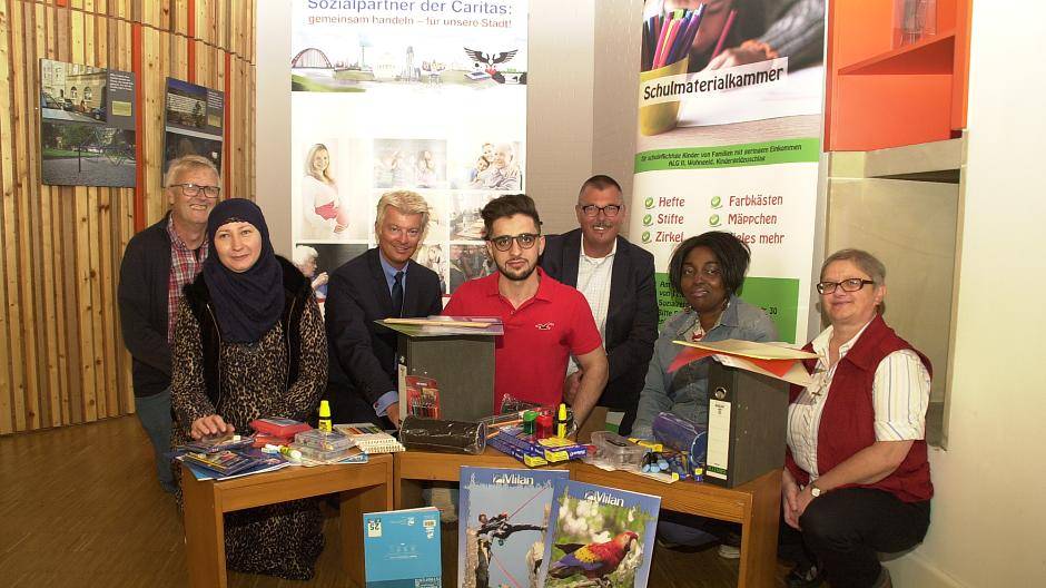 Klaus Peter Bongardt, Gemeindecaritas, Mutter Marina, Dr. Joachim Bonn, Vorstandsvorsitzender der Sparkasse Duisburg, Saaed, Praktikant in der Schulmaterialkammer, Ulrich Fuest, Caritasdirektor, Mutter Chantal und Schwester Martina Paul, Leitung Sozialzentrum St. Peter, mit einer Auswahl des Schulmaterials, das dieser Tage vergeben wurde (vl).